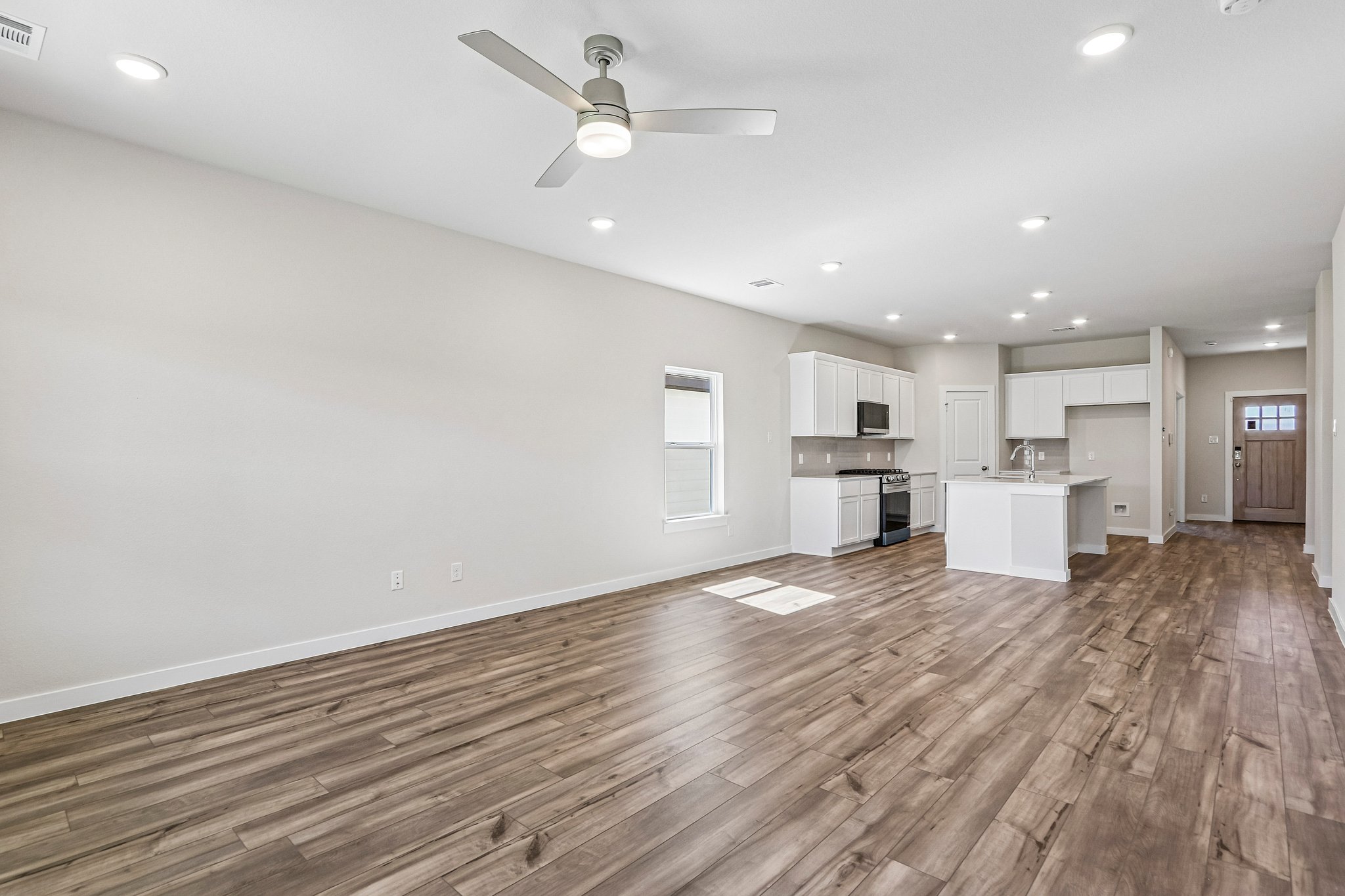 A large empty room with a wood floor and a ceiling fan.
