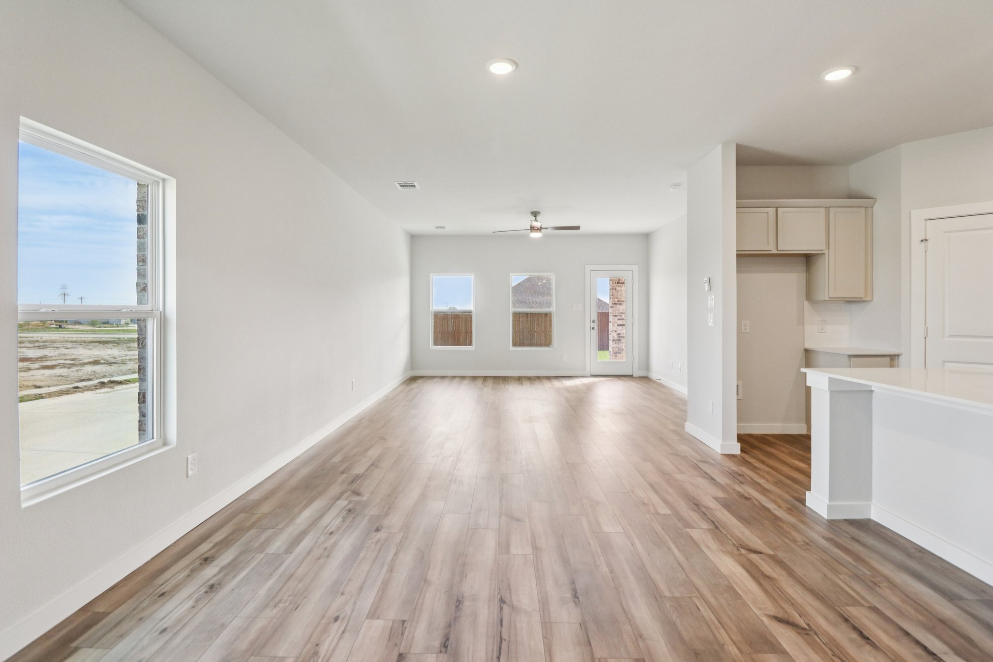 A room with a wood floor and white cabinets.