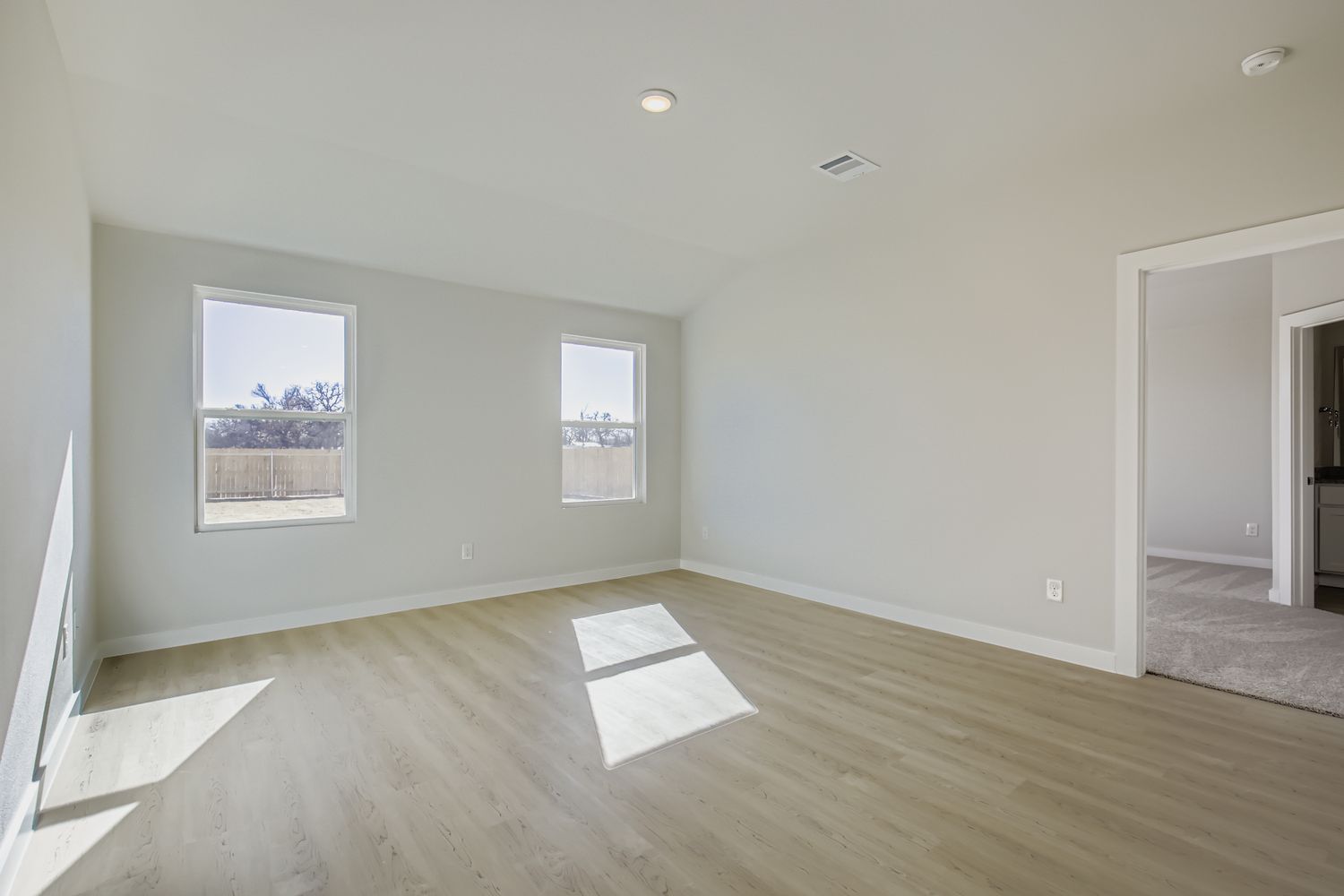 A room with a wood floor and a white wall with a painting on it.