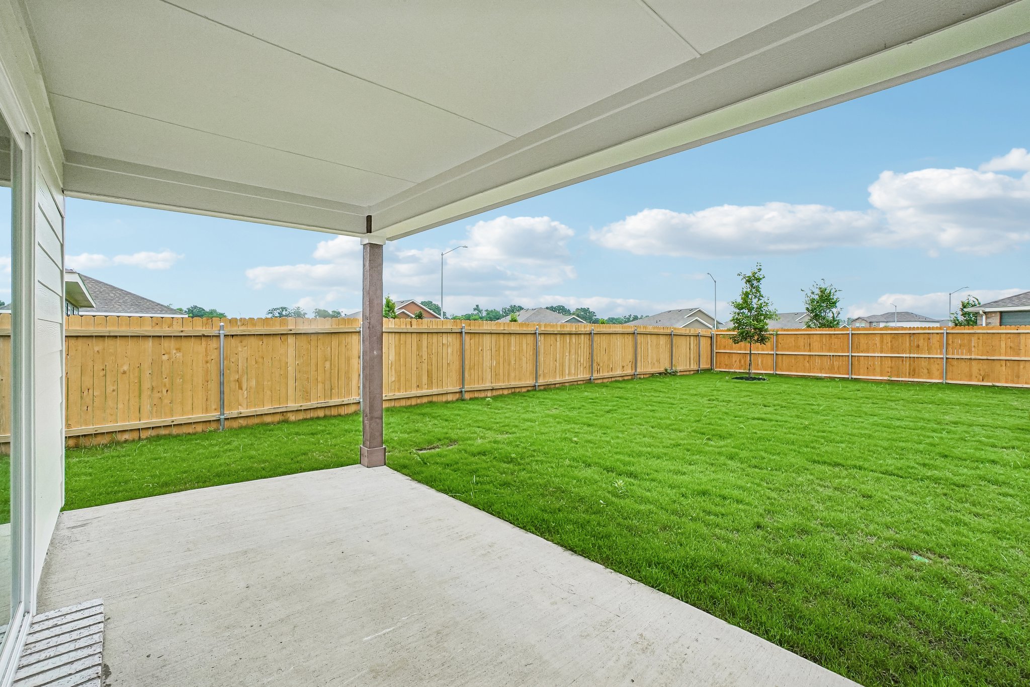 A fenced in yard with a walkway and grass and a building.