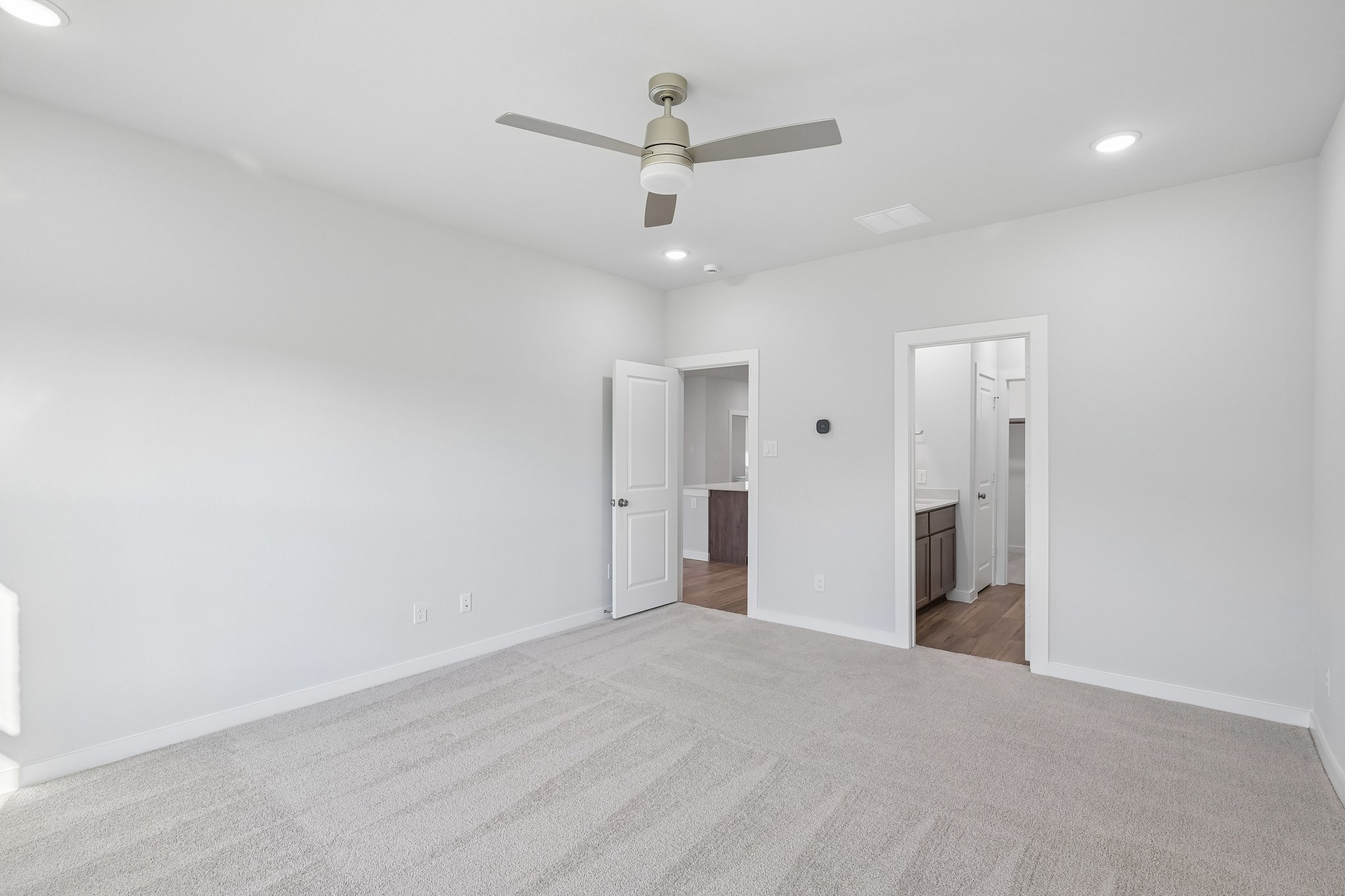 A room with a ceiling fan and a carpet.