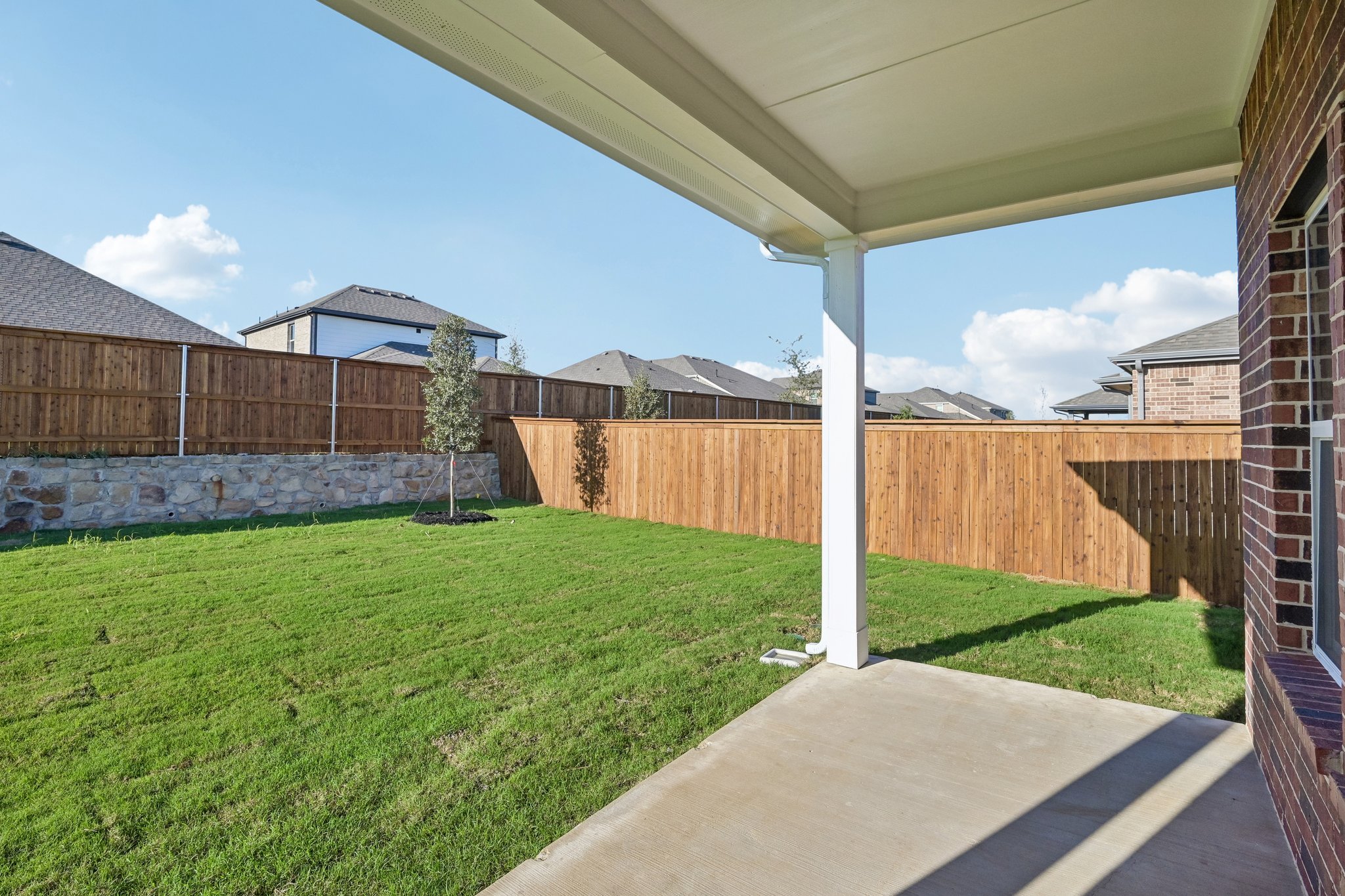 A fenced in yard with a walkway and a building in the background.