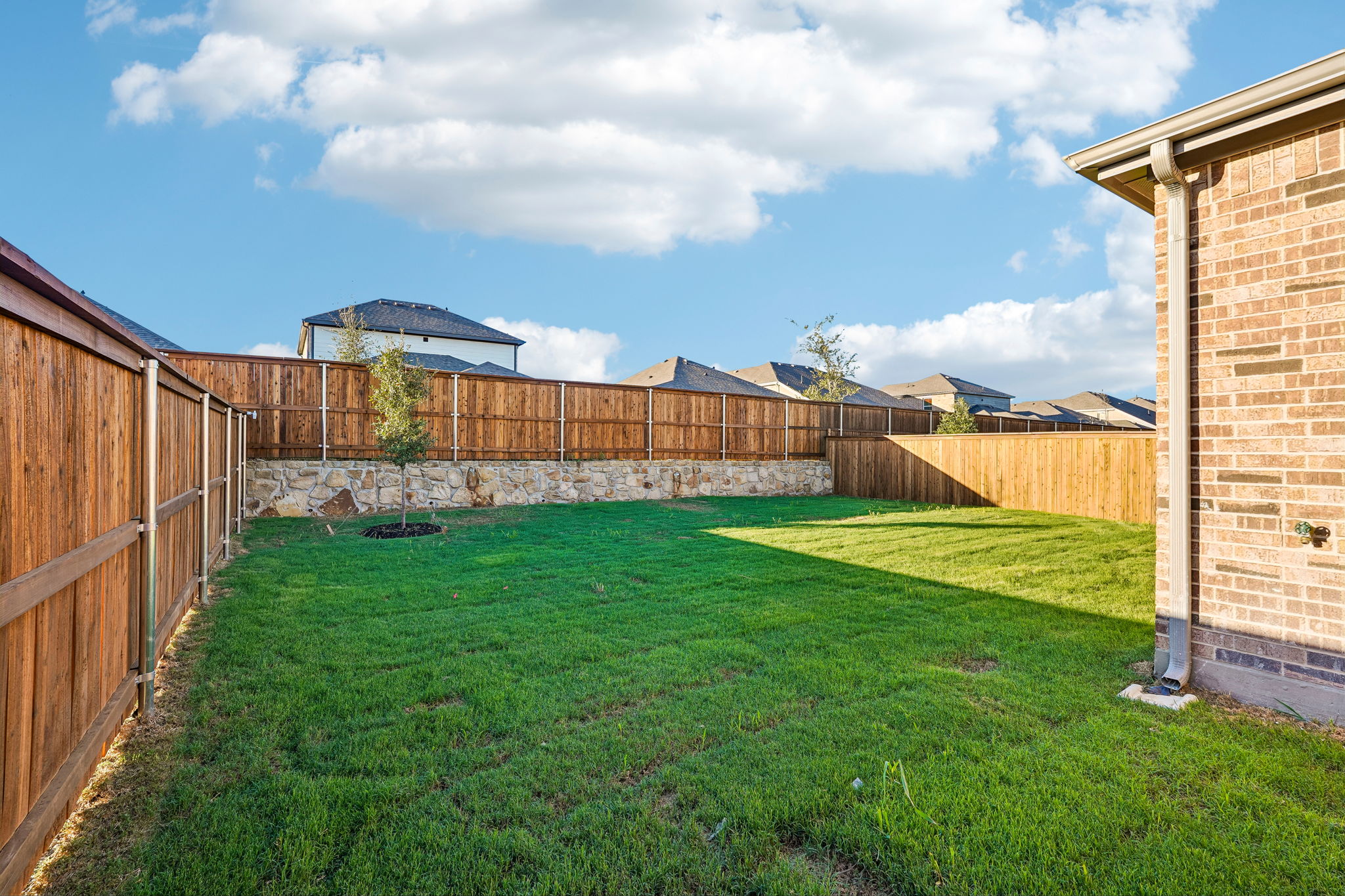 A fenced yard with a brick wall and a brick building.