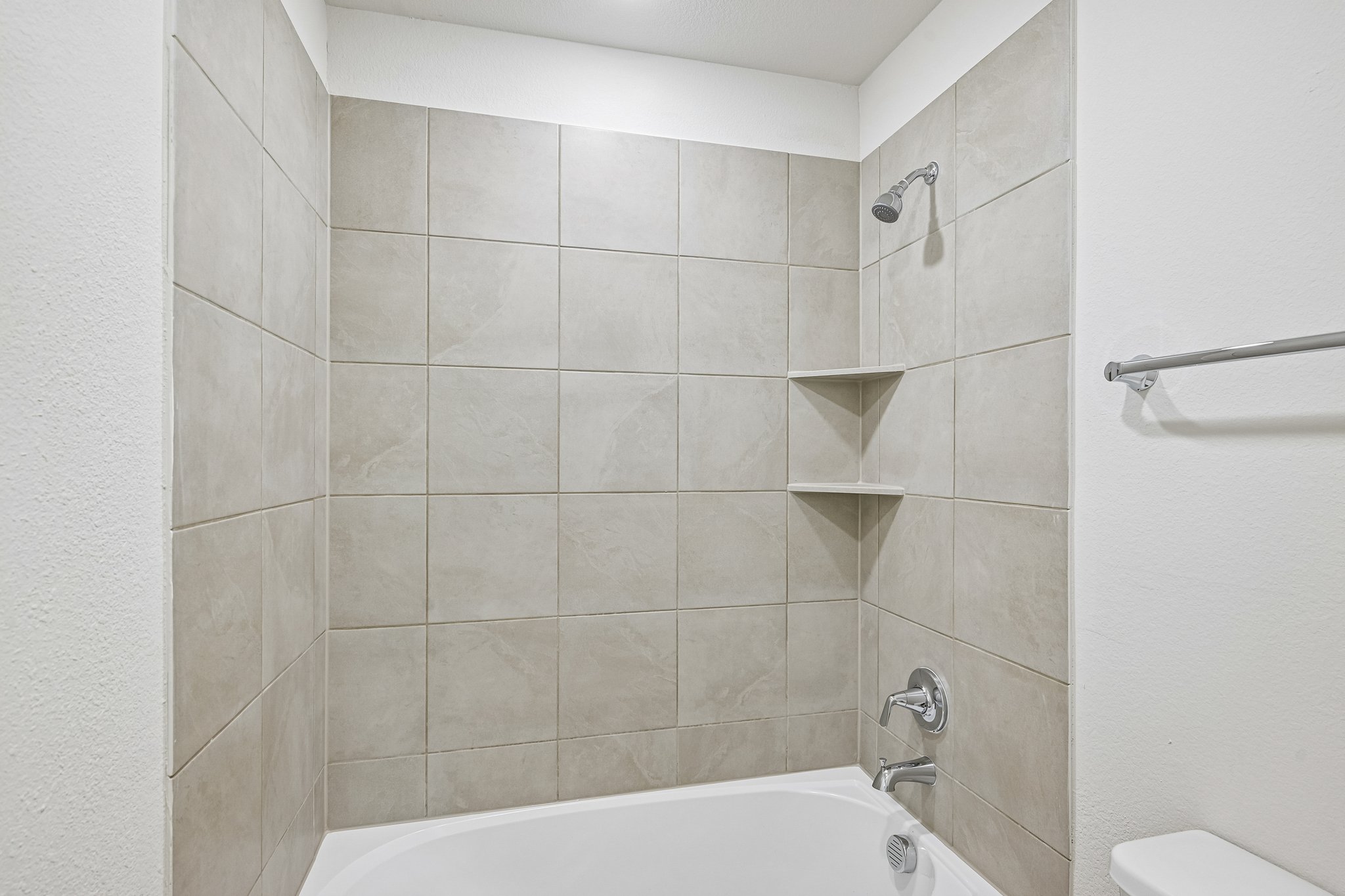 A bathroom with a bathtub and shower unit.
