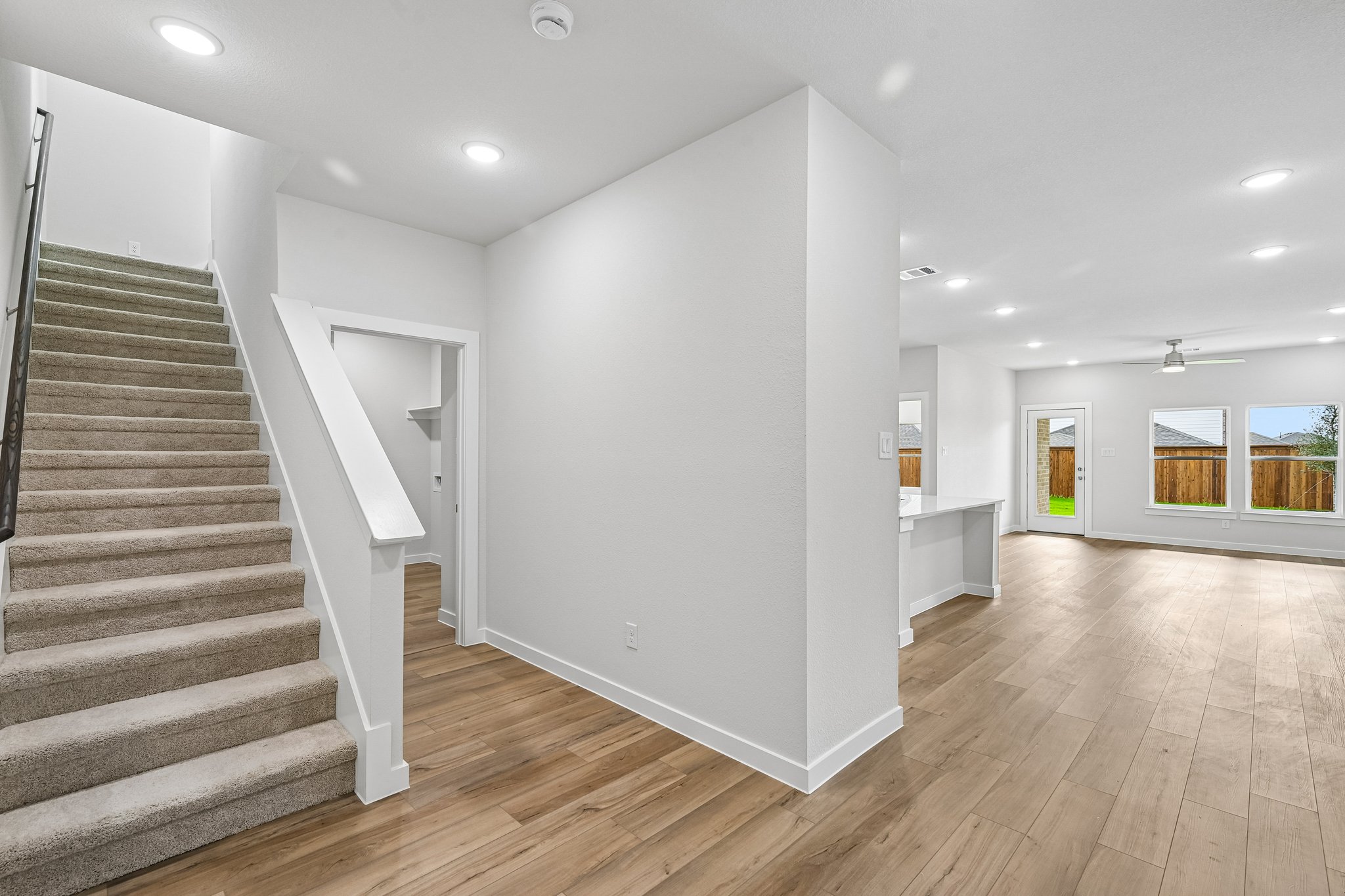 A large white room with a wood floor and a staircase.