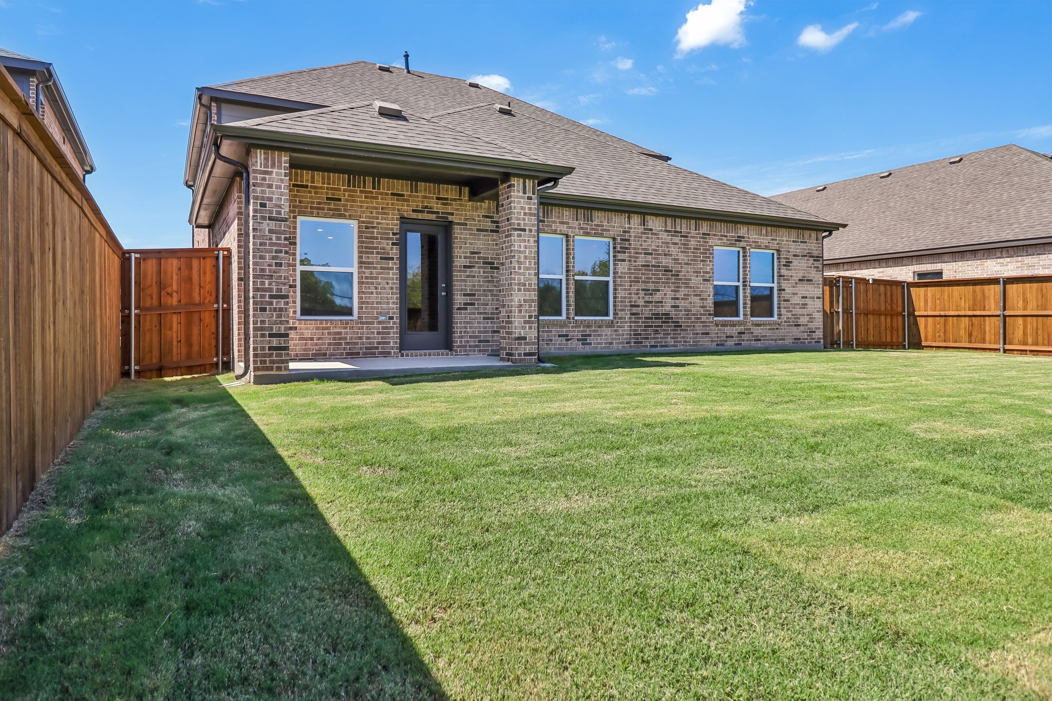 A brick house with a green lawn.