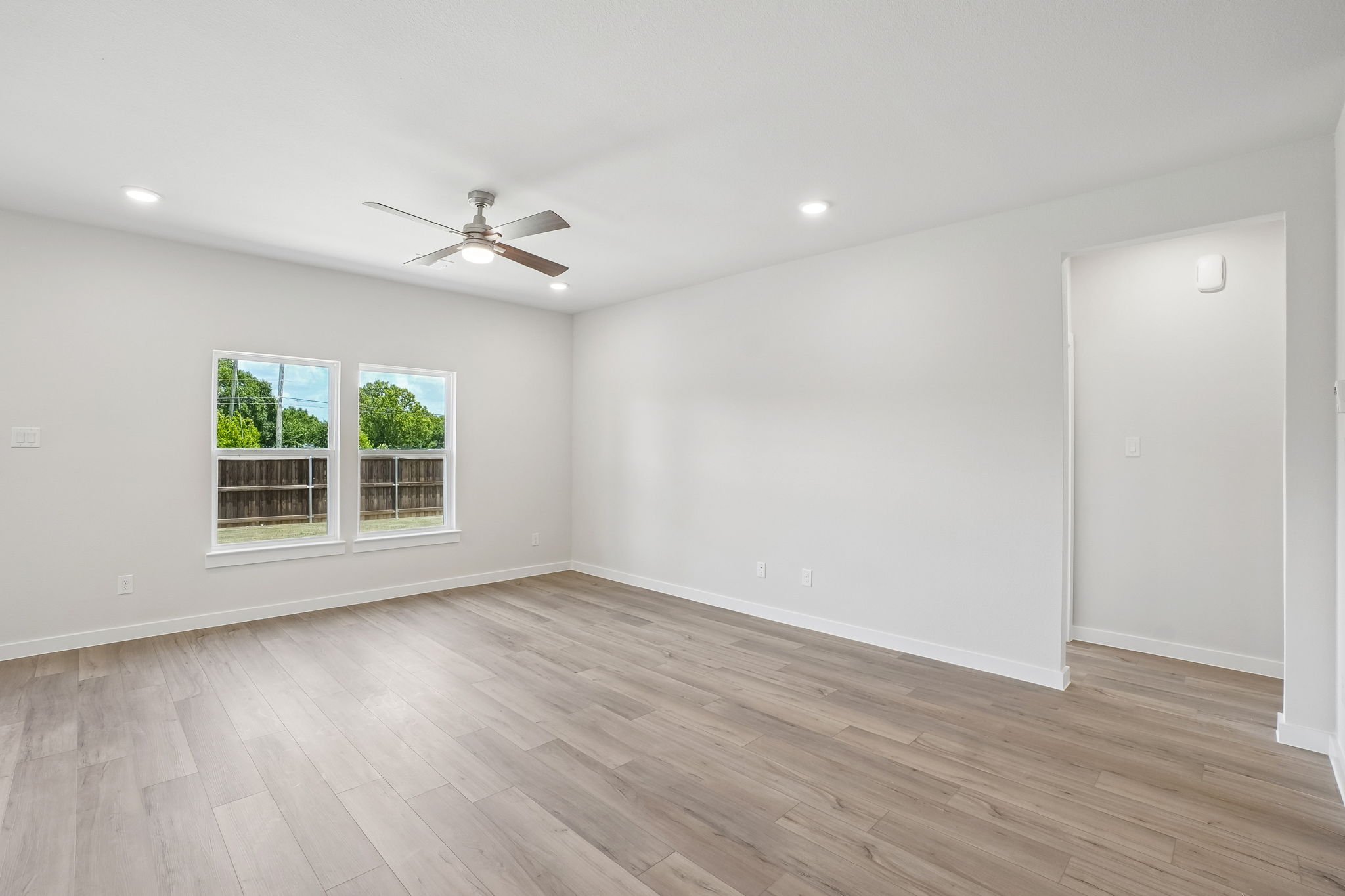 A room with a wood floor and a ceiling fan.