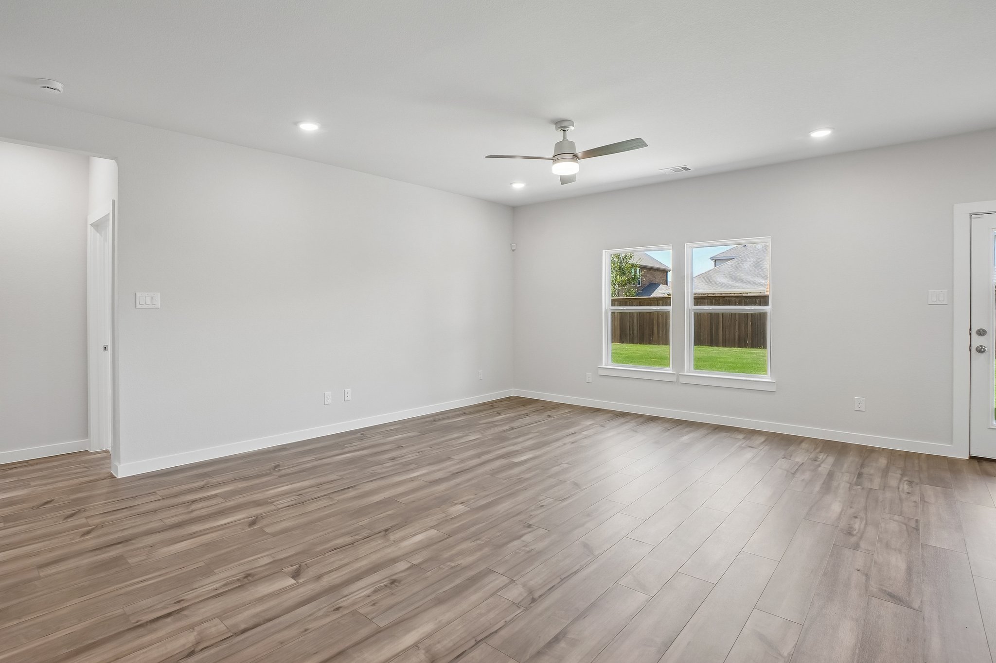 A room with a wood floor and a wood floor with a ceiling fan.