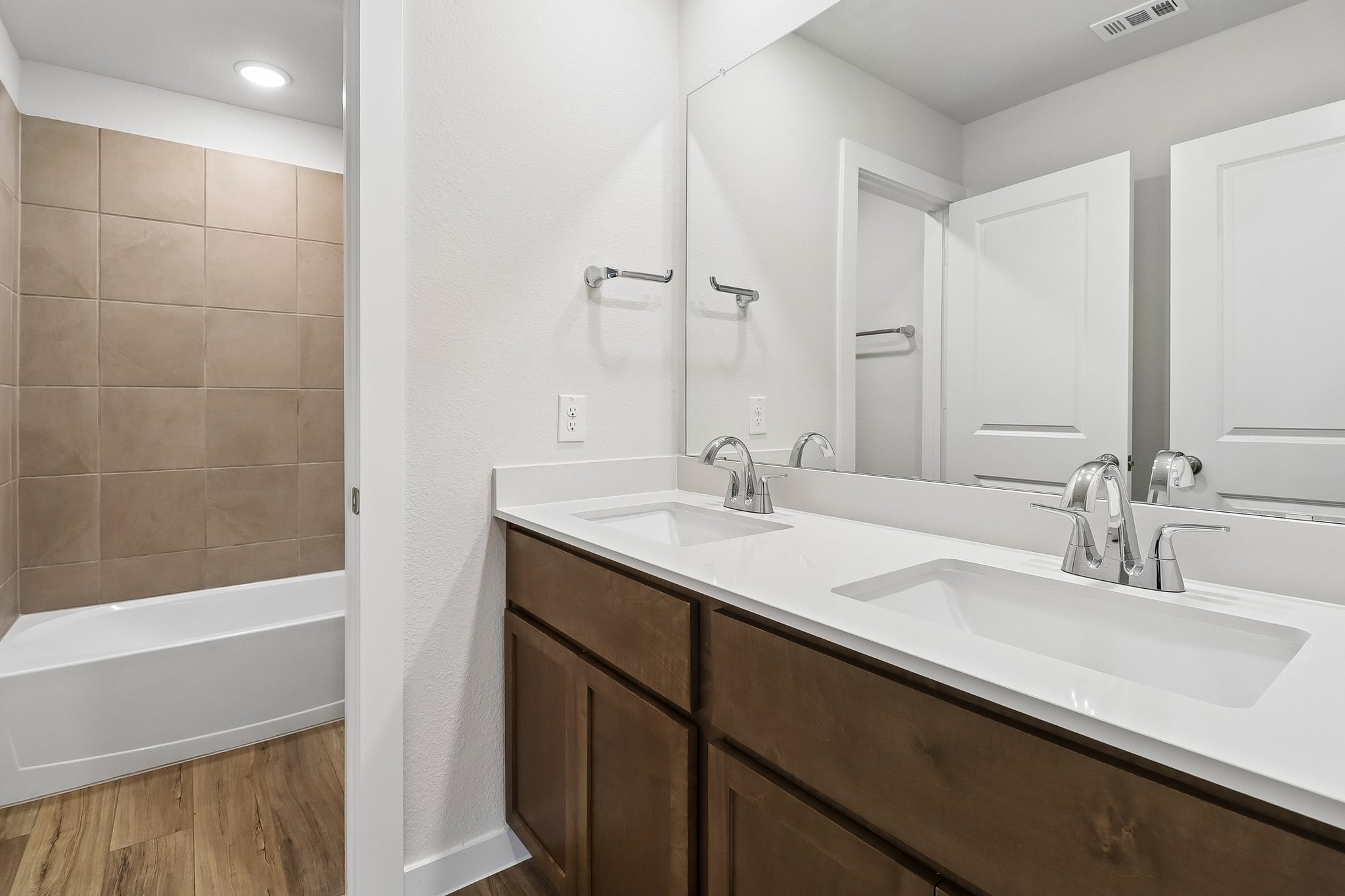 A bathroom with a tub sink and mirror.