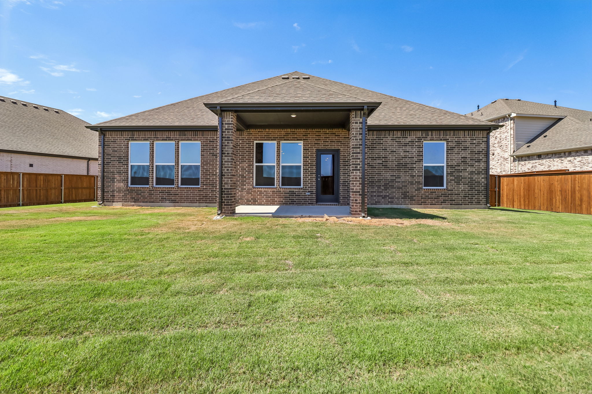 A brick house with a grass yard.