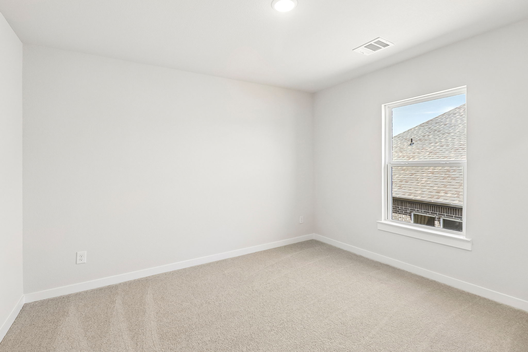 A room with a window and a light on the wall.