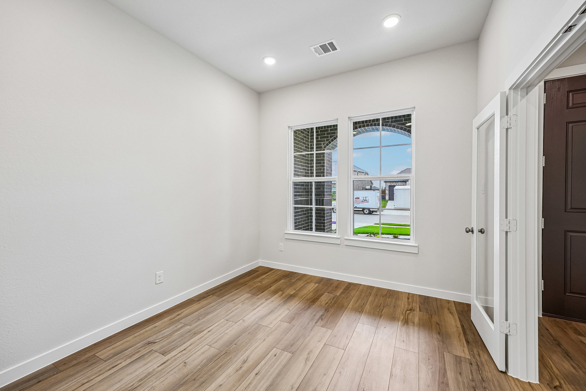 A room with a wood floor and a window with a view of the water.