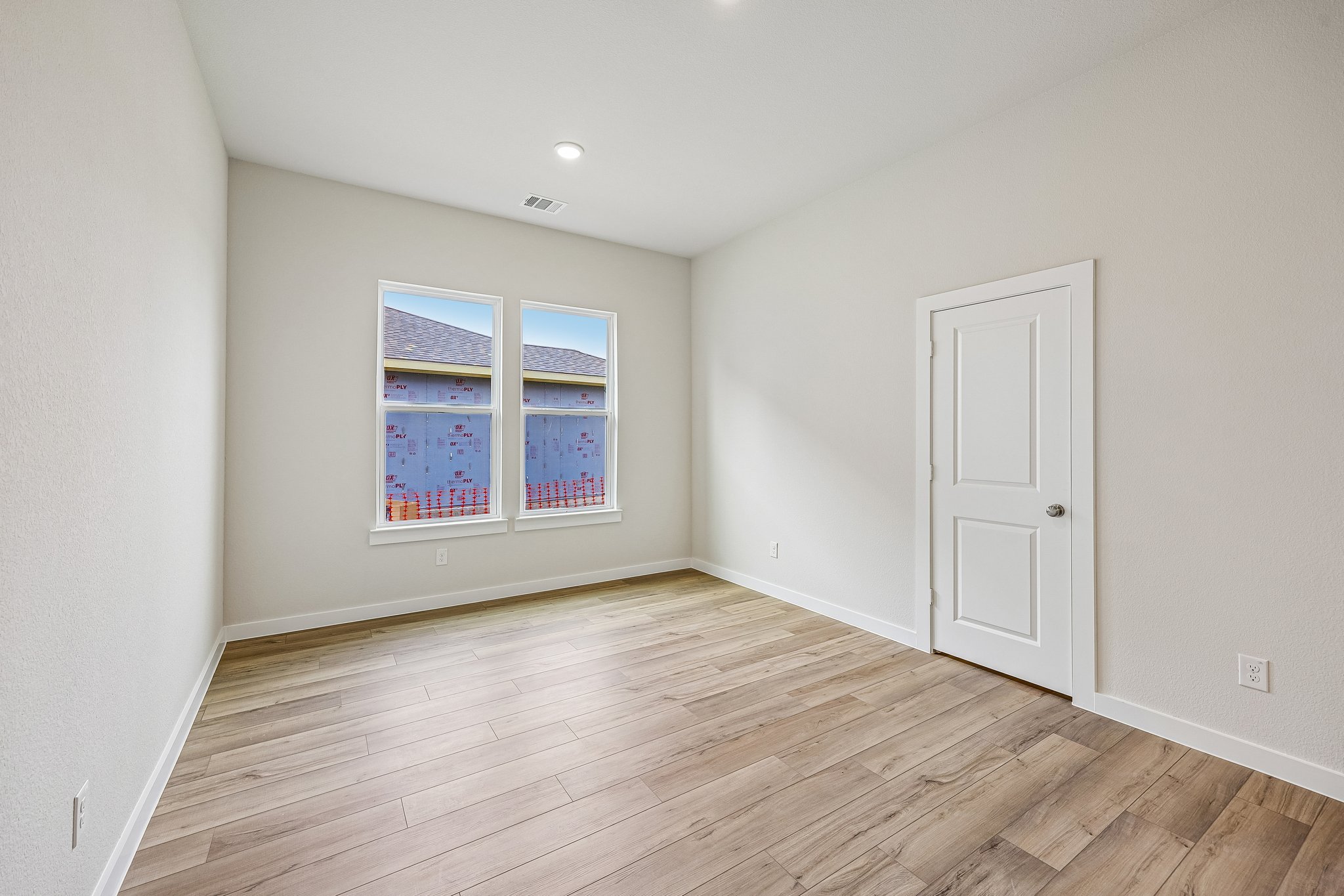 A room with a wood floor and a white door with a window.