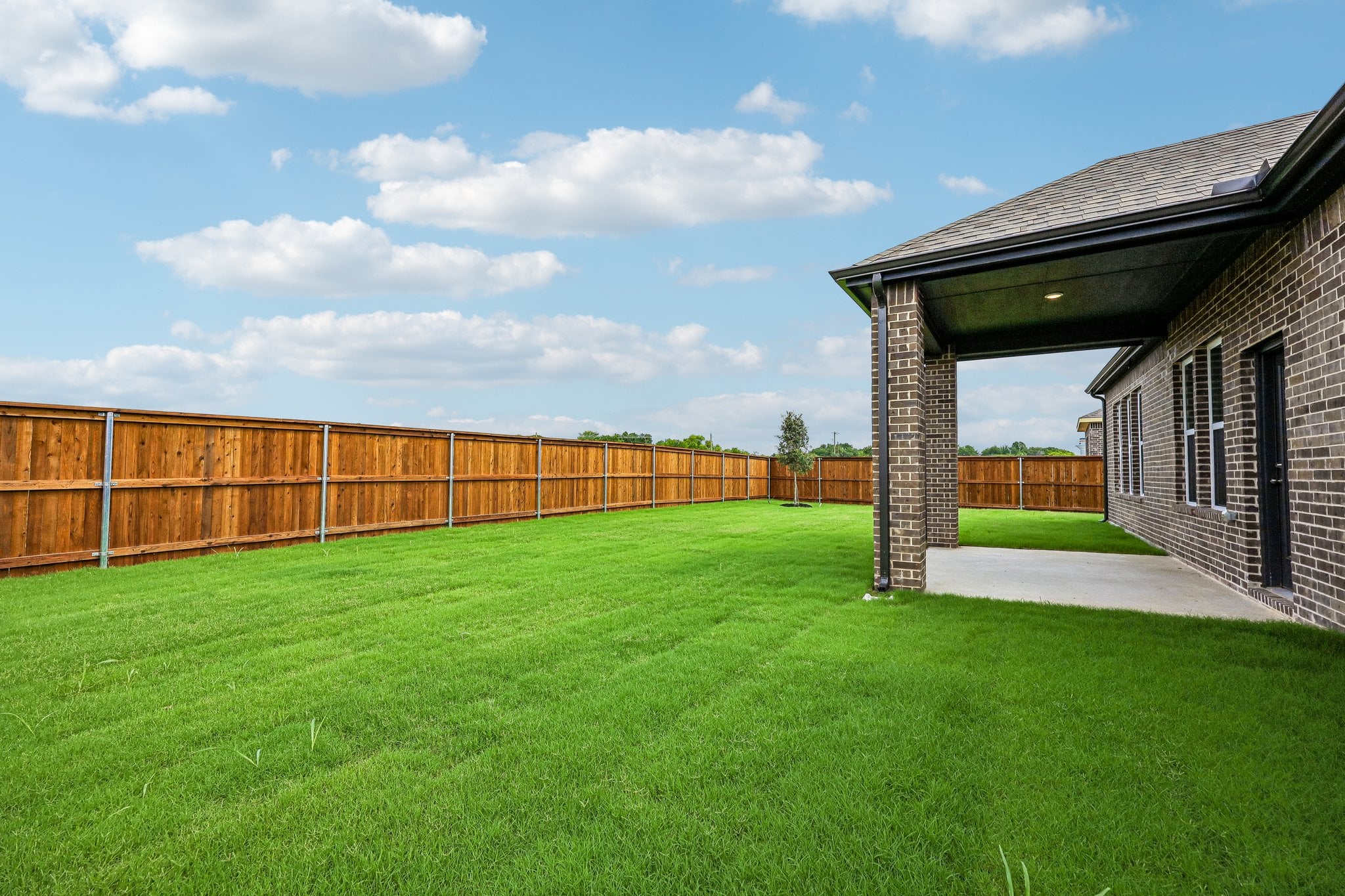 A fenced in yard with a brick building and a brick building.