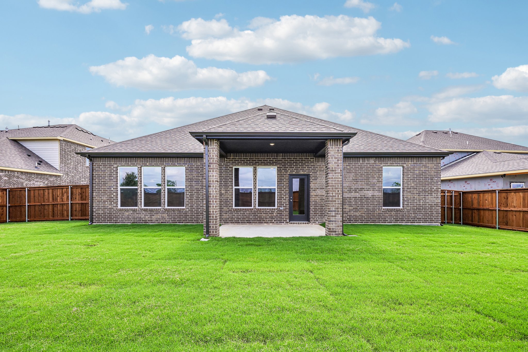 A brick house with a green lawn.