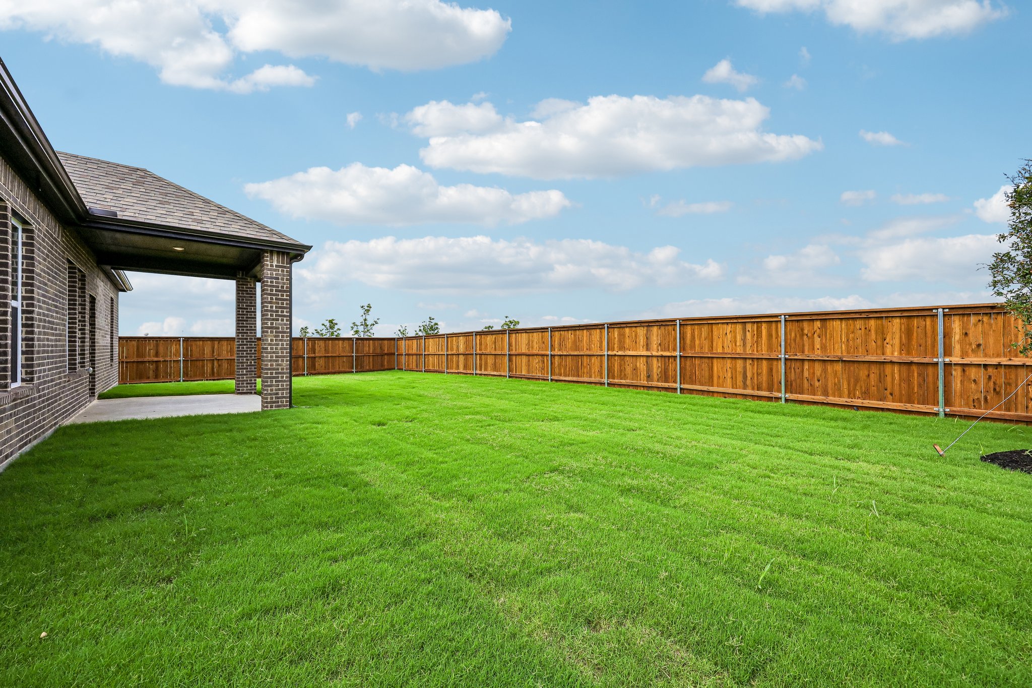 A fenced in yard with a house and a building in the background.