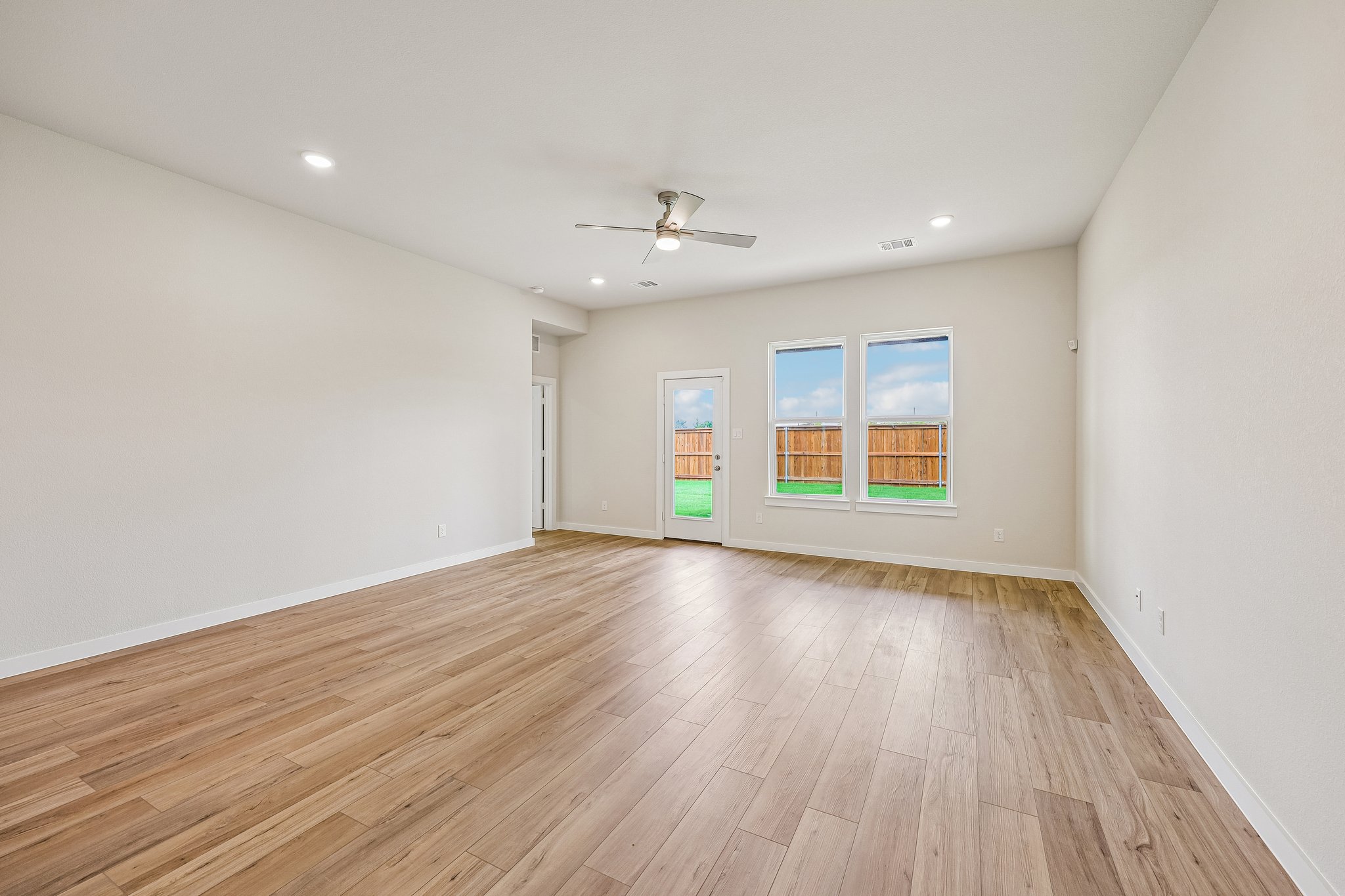 A room with a wood floor and a ceiling fan.