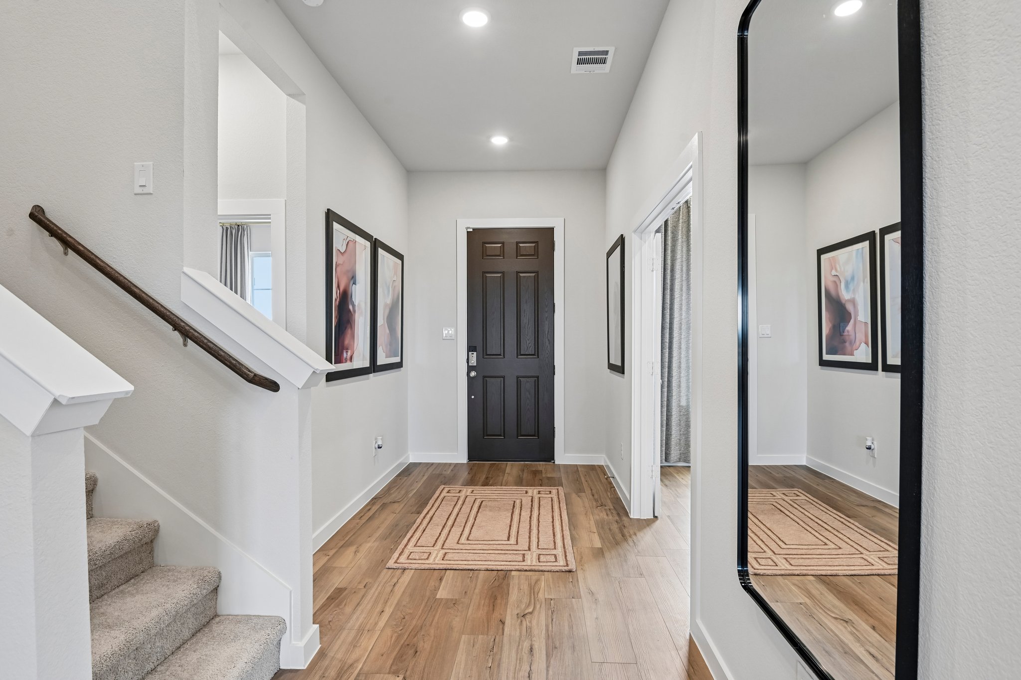 A hallway with a wood floor and a wood staircase.