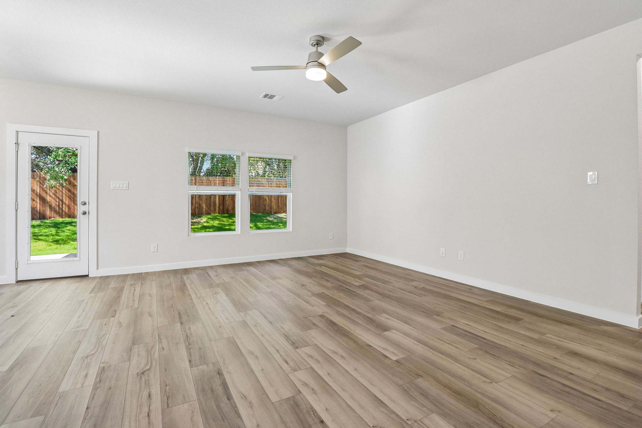 A room with a wood floor and a ceiling fan and a wood floor.