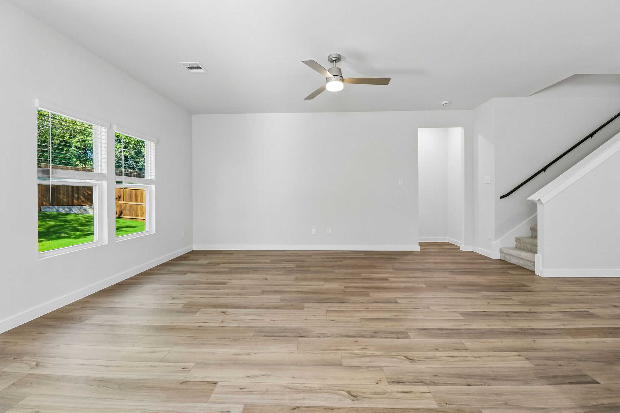 A room with a wood floor and a wood floor with a ceiling fan.