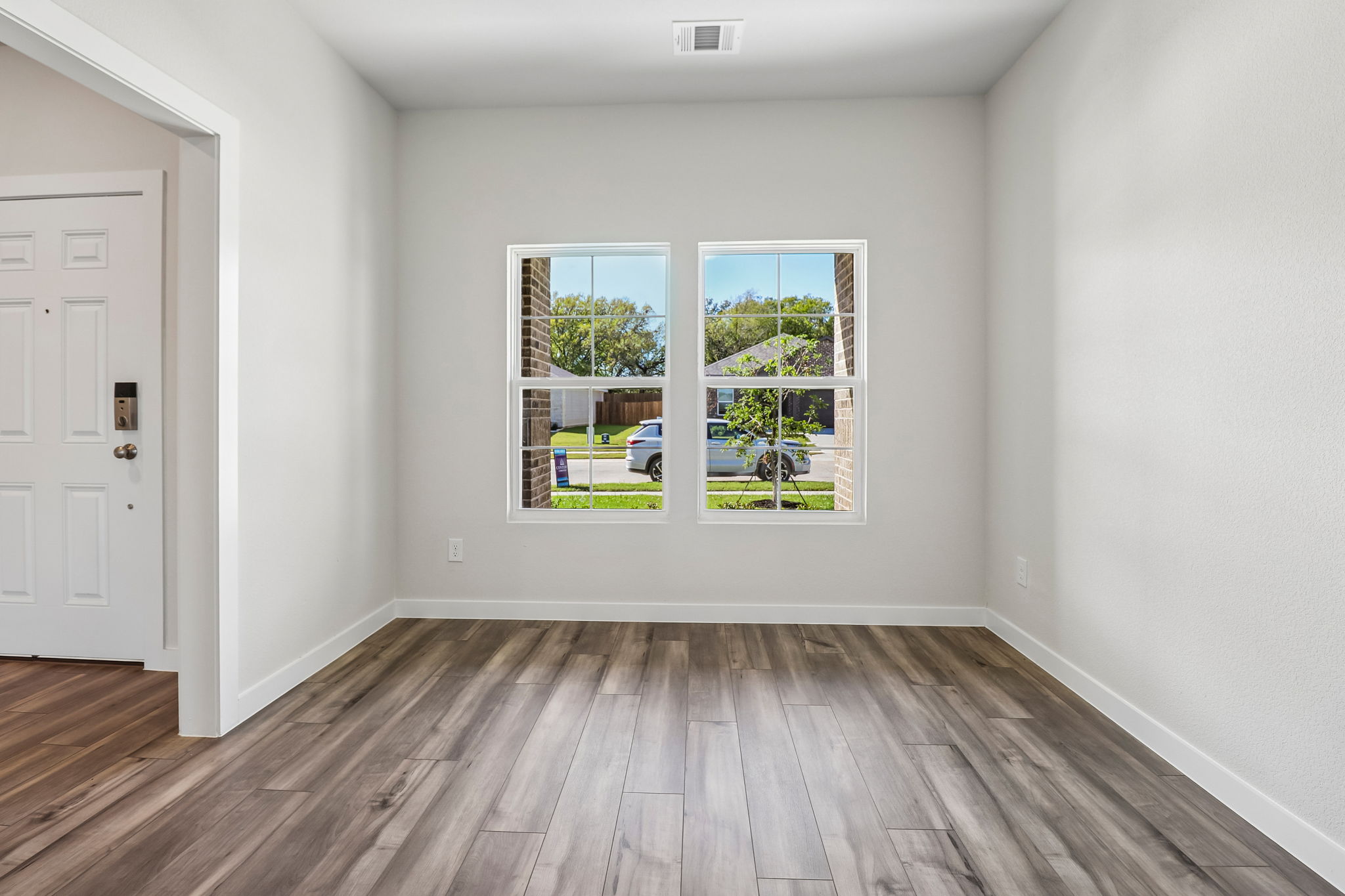 A room with a window and a wood floor.