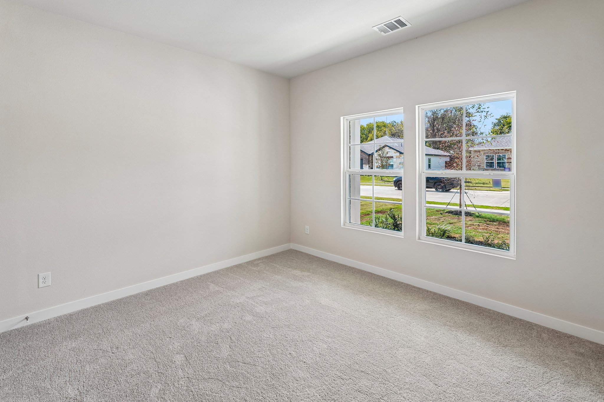 A room with a window and a white wall with a plant.