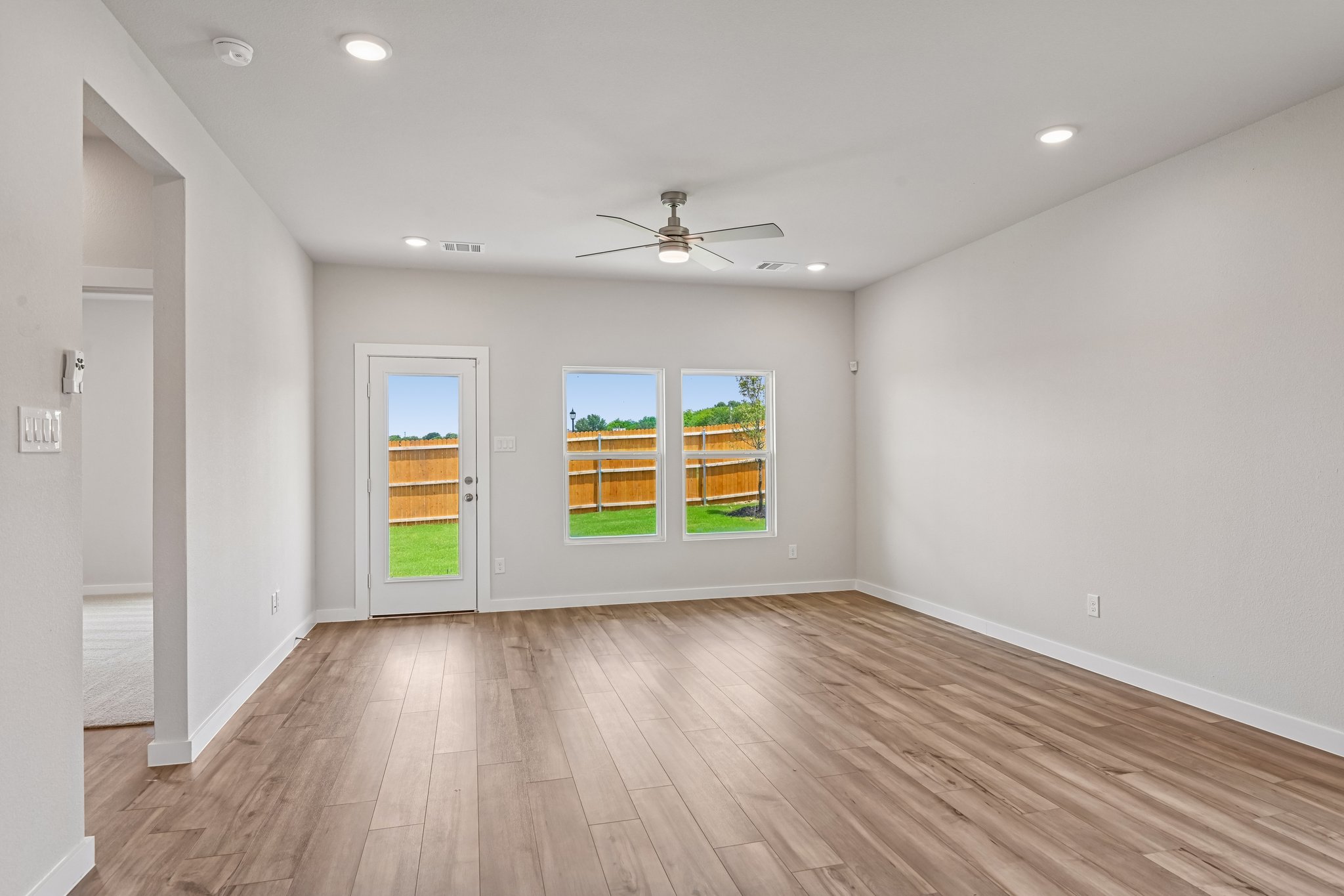 A room with a wood floor and a wood floor with a ceiling fan.