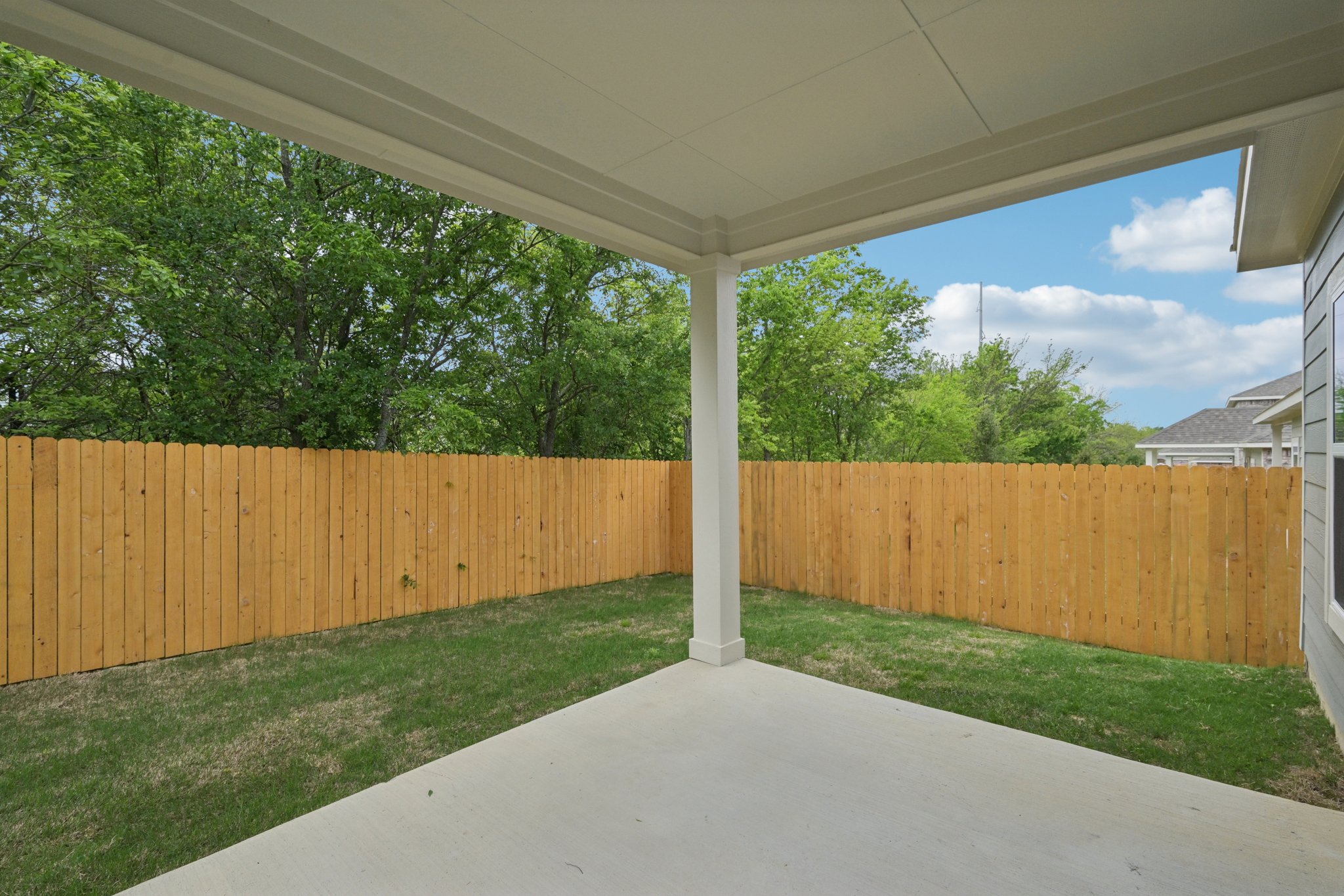 A fenced in yard with a wood fence and trees in the background.