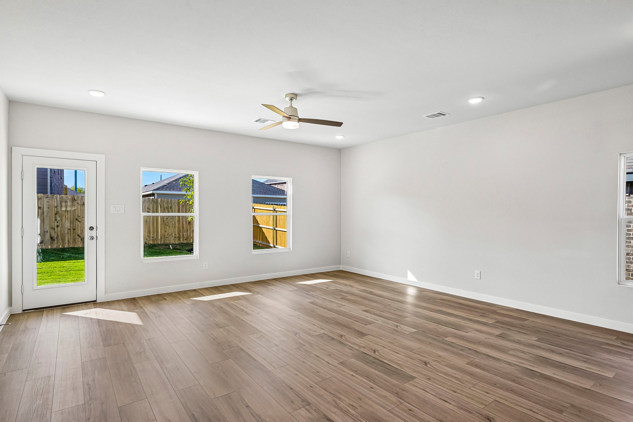 A room with a wood floor and a wood floor with a ceiling fan.