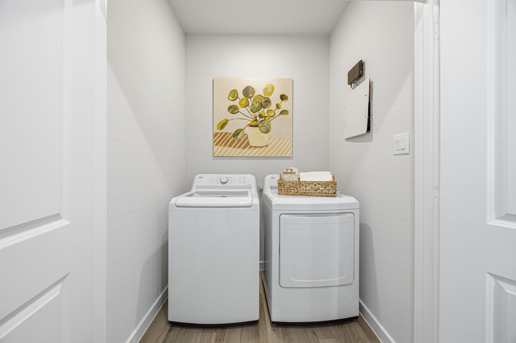A laundry room with a basket on the top of the dryer.