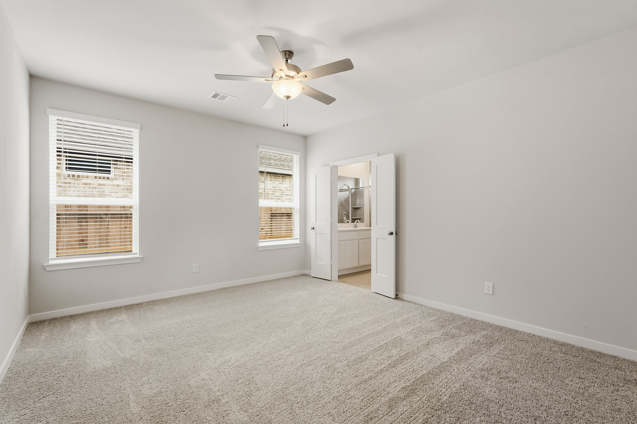 A large living room with a ceiling fan and a refrigerator.