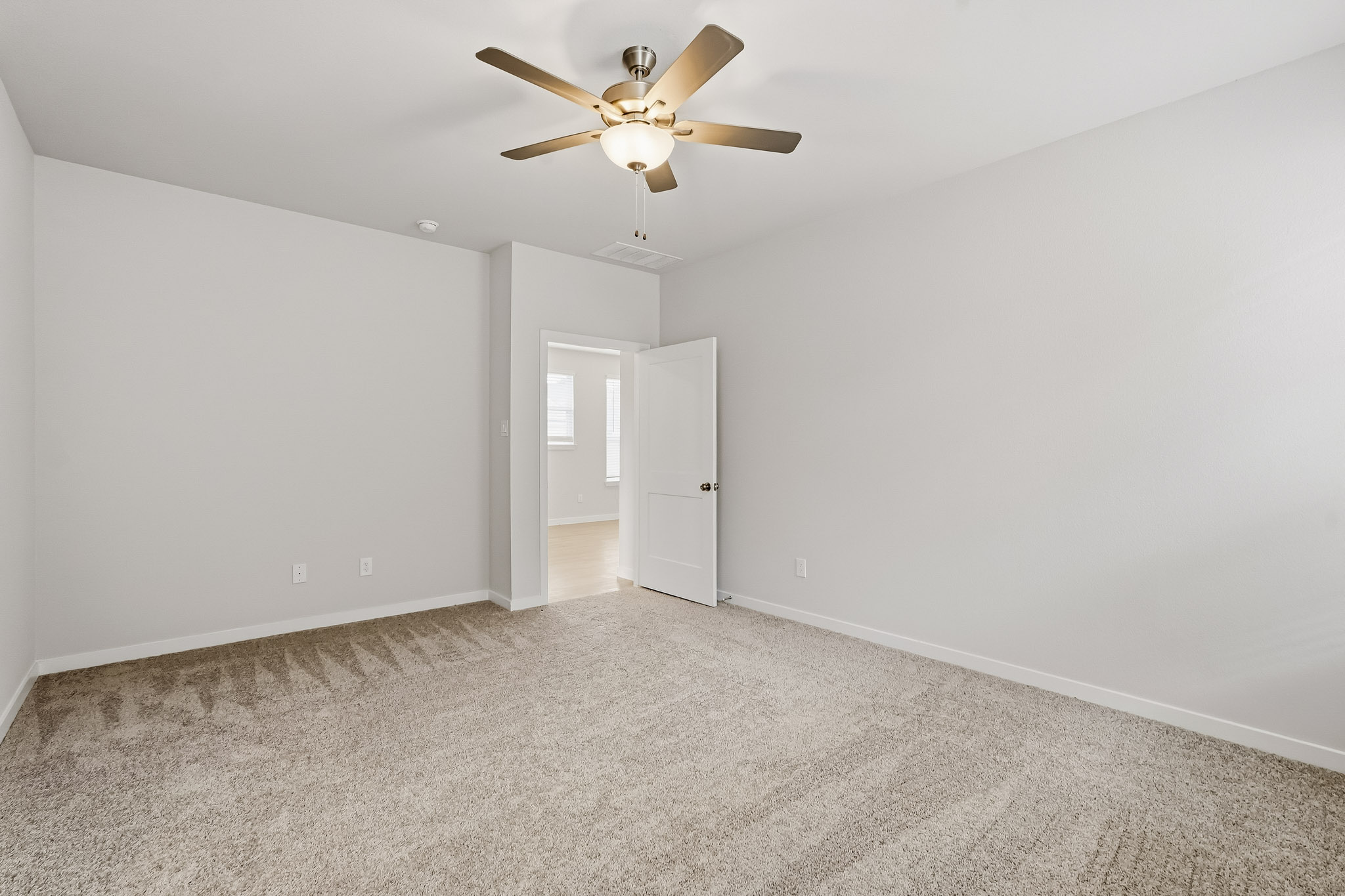 A room with a ceiling fan and a door.