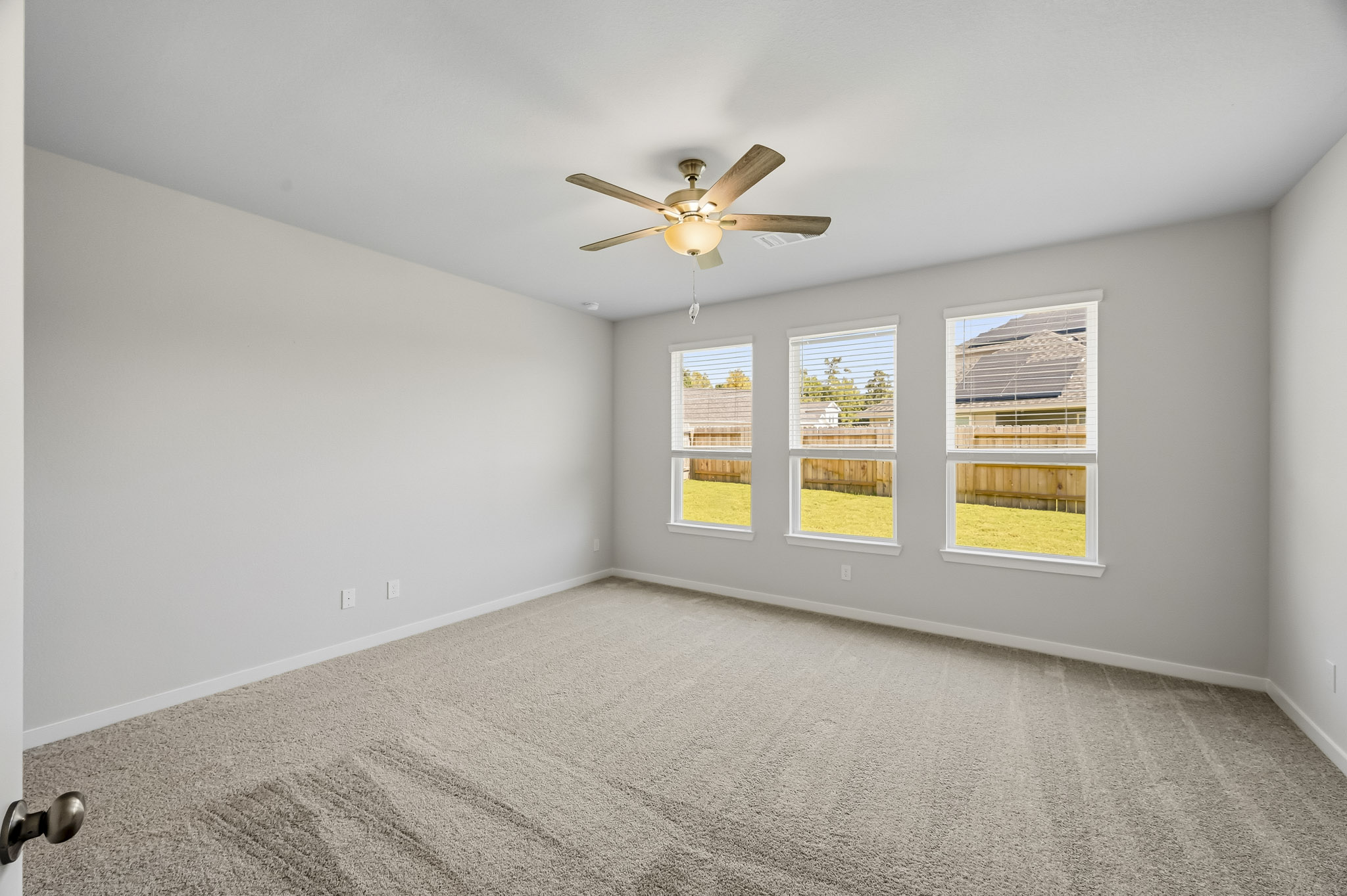 A room with a ceiling fan and a window with a light.