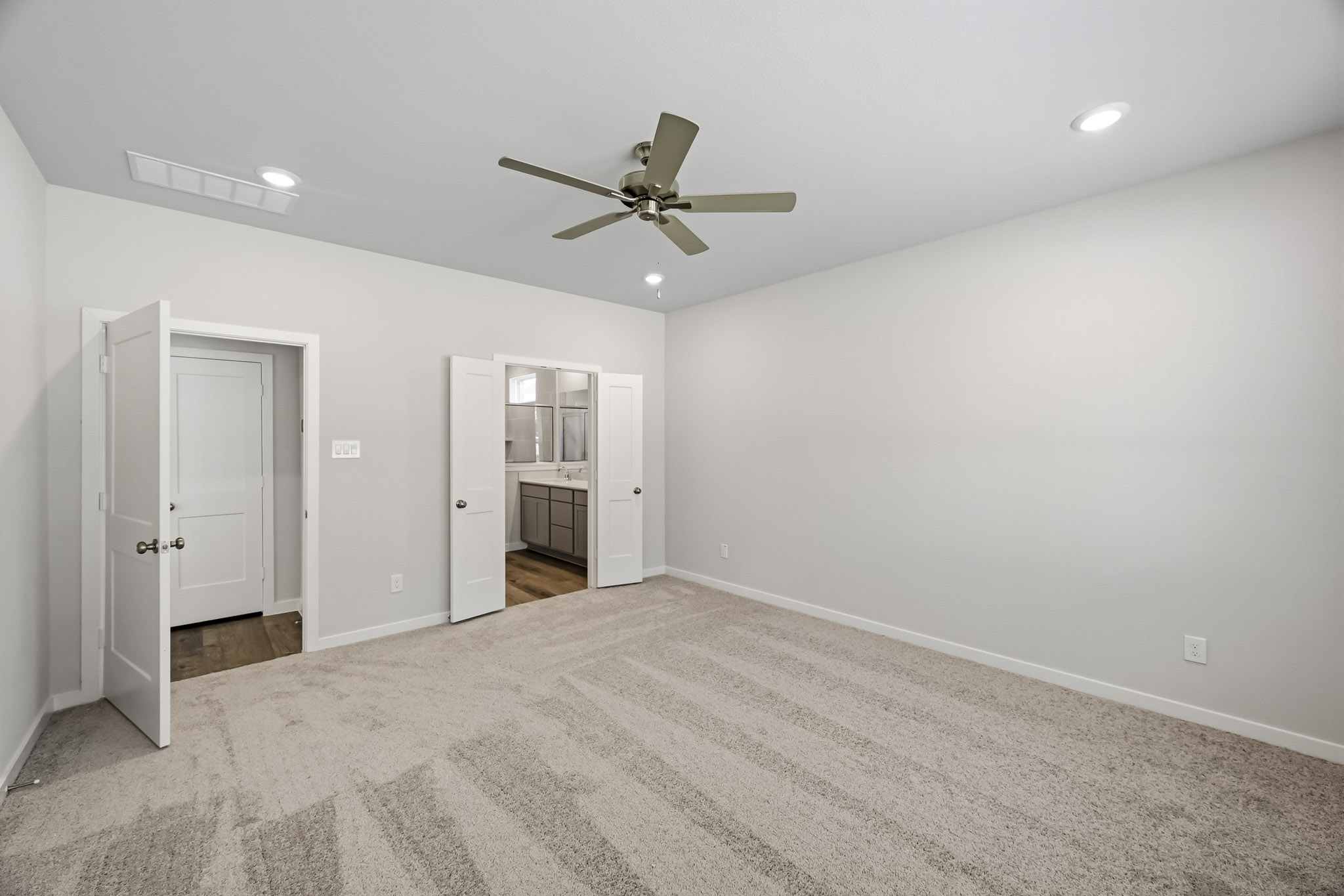 A room with a ceiling fan and white walls.