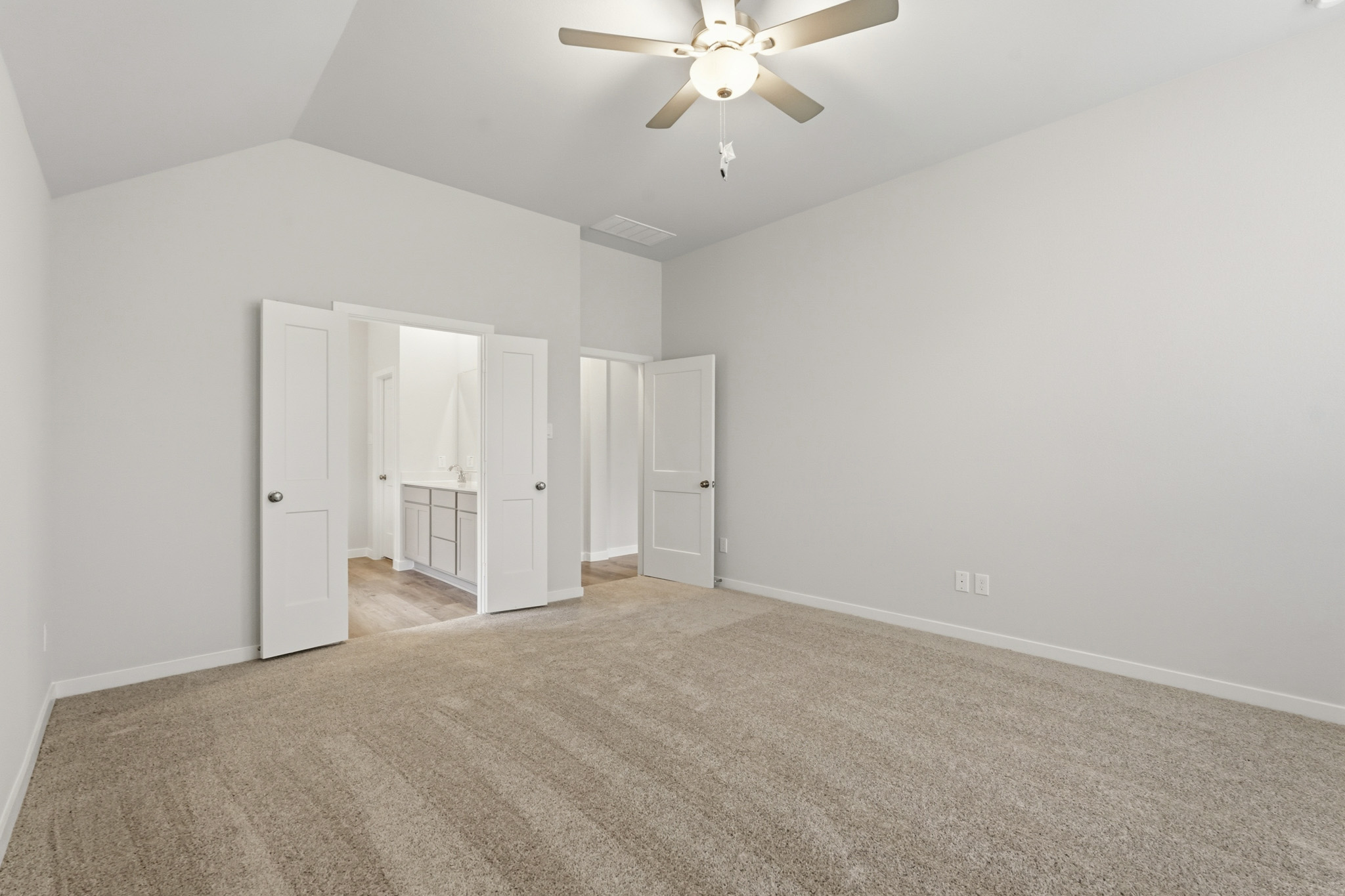 A room with a ceiling fan and white cabinets.