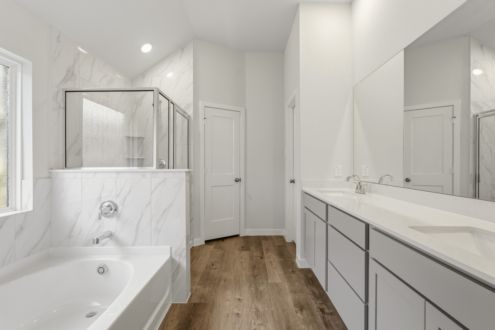 A bathroom with a tub sink and mirror.