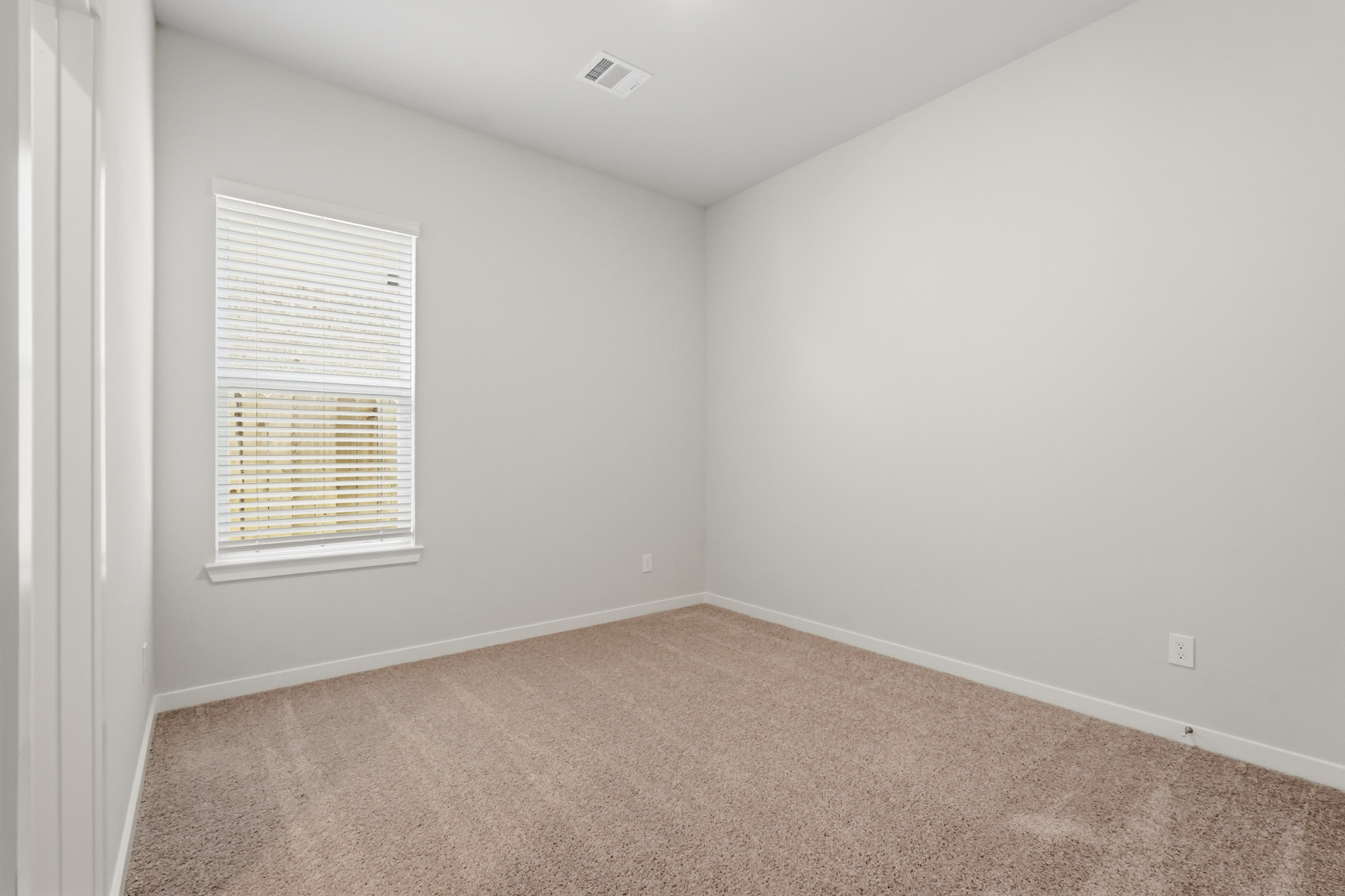 A room with a carpet and a window.