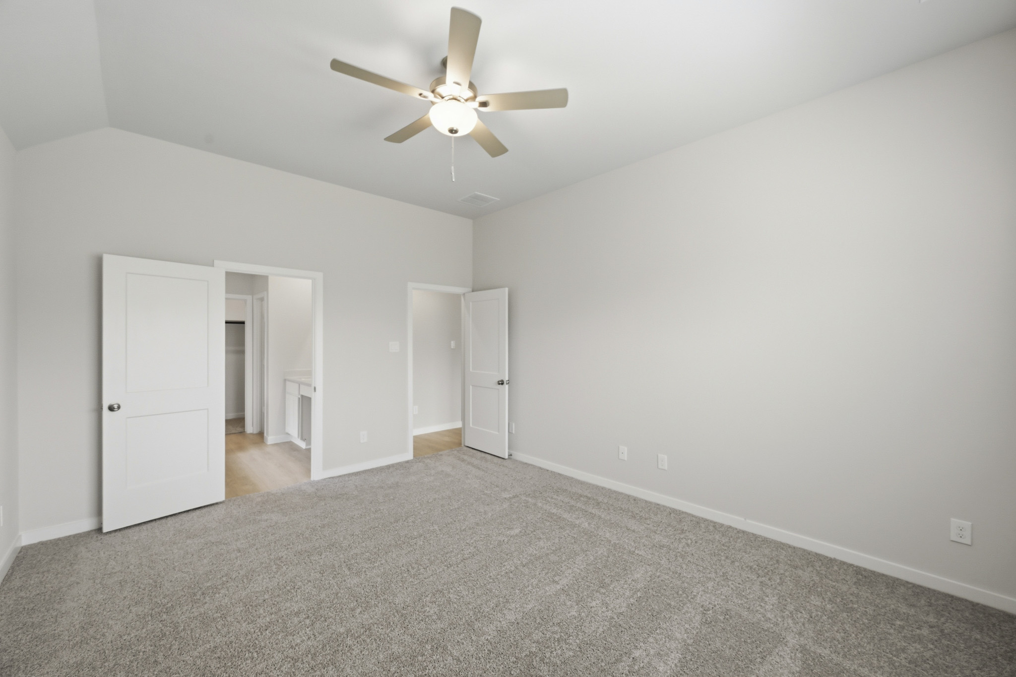 A room with a ceiling fan and white cabinets.