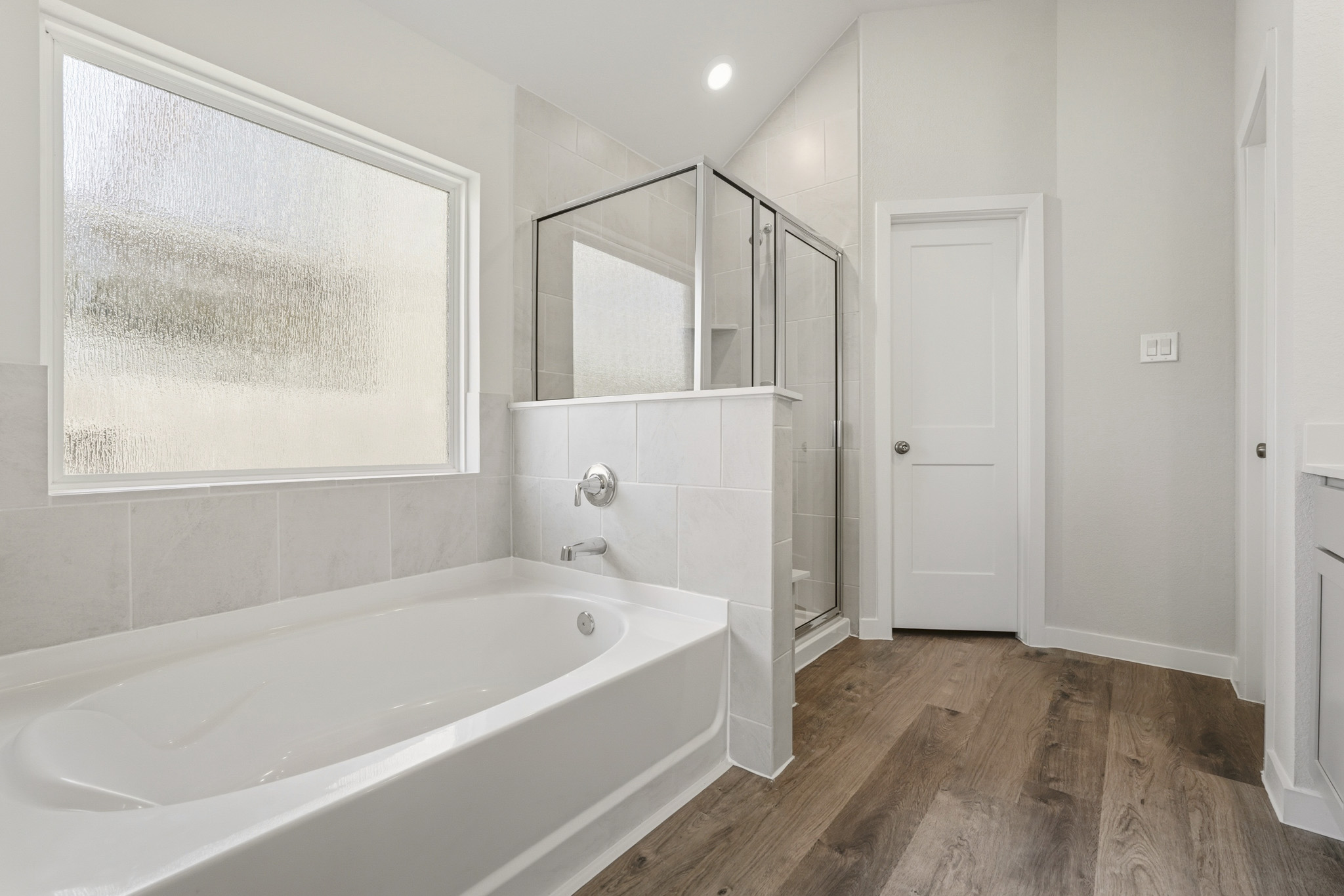 A bathroom with a tub and a mirror.