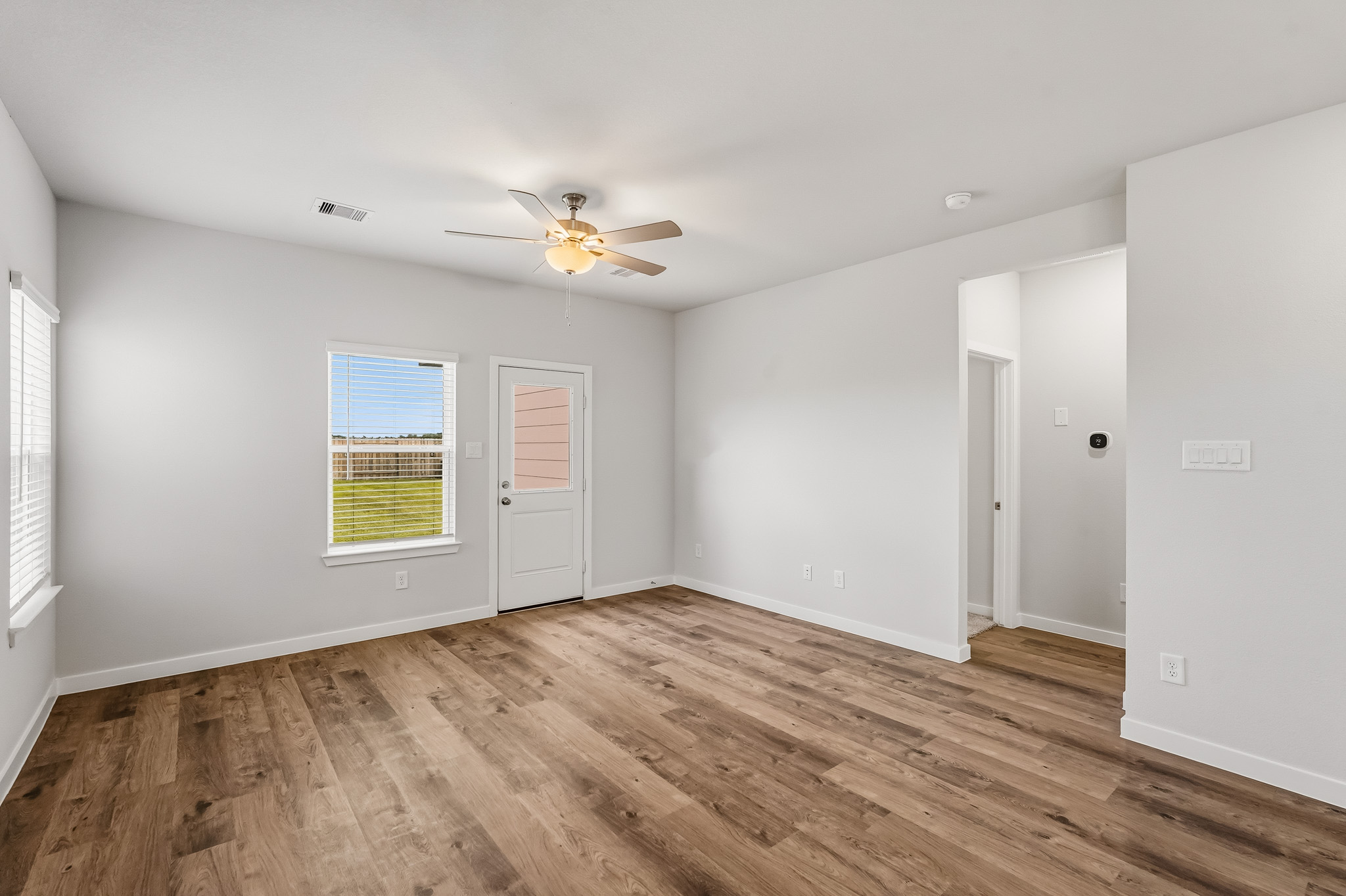 A room with a wood floor and a ceiling fan.