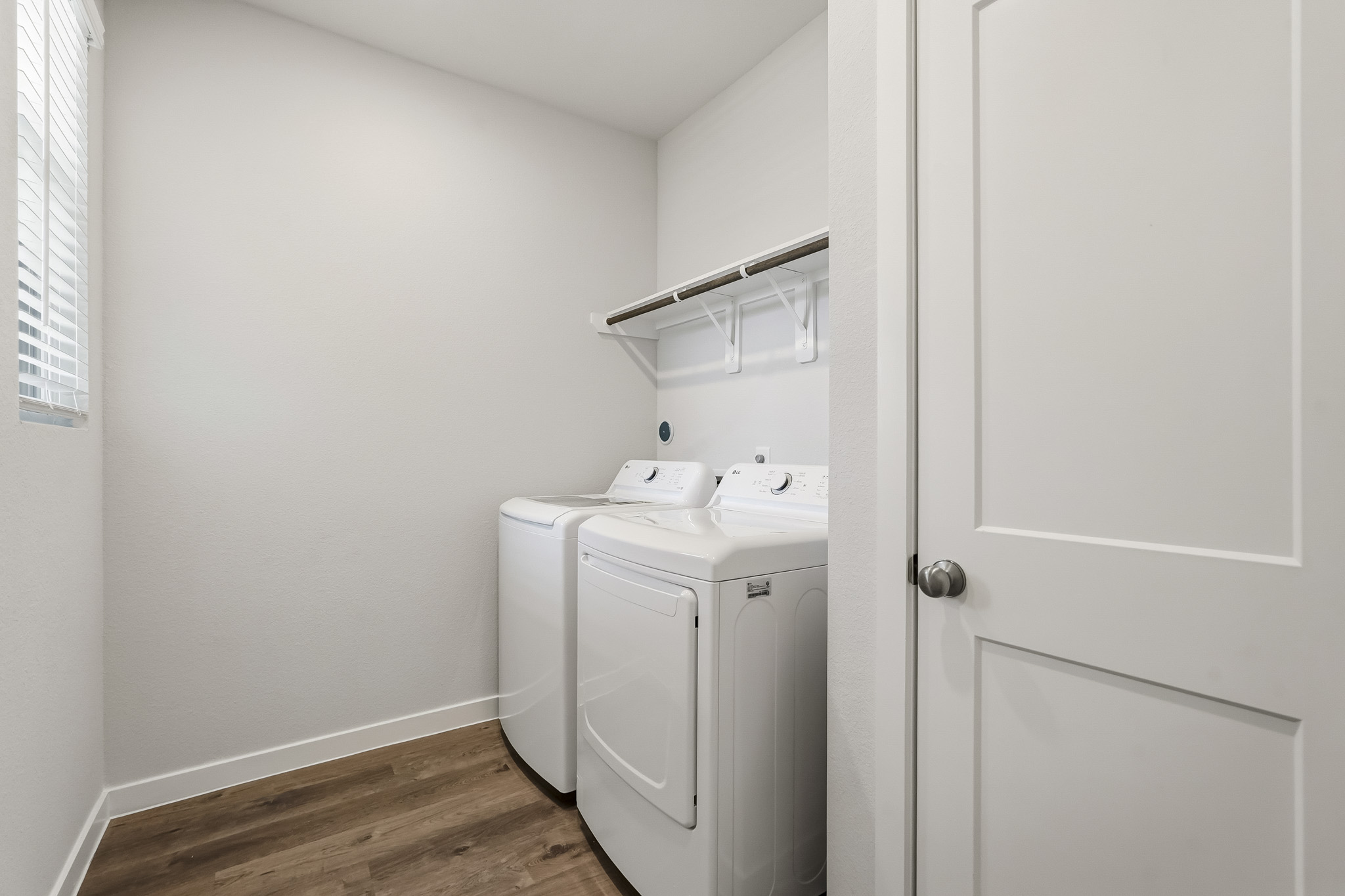 A white laundry room with a sink and a washer.