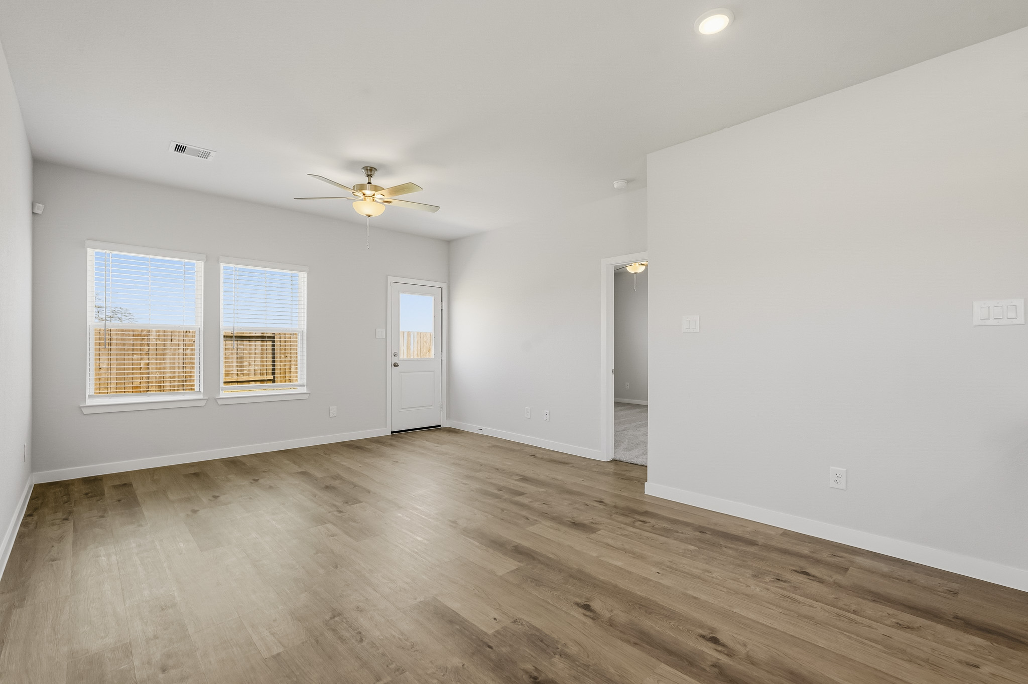 A room with a wood floor and a ceiling fan.