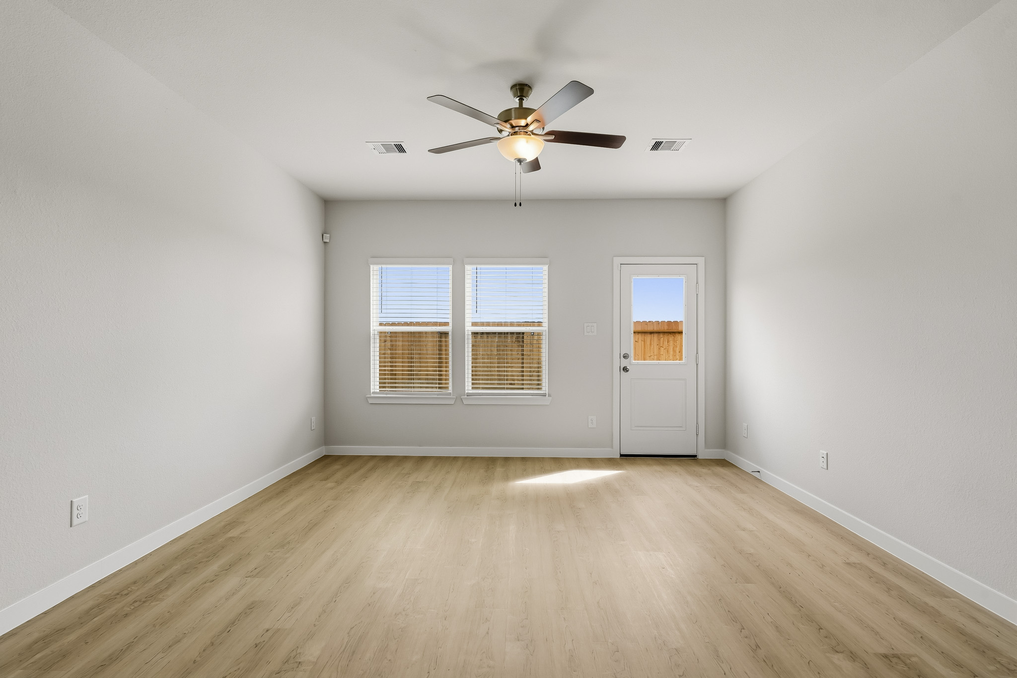 A room with a ceiling fan and a wood floor.