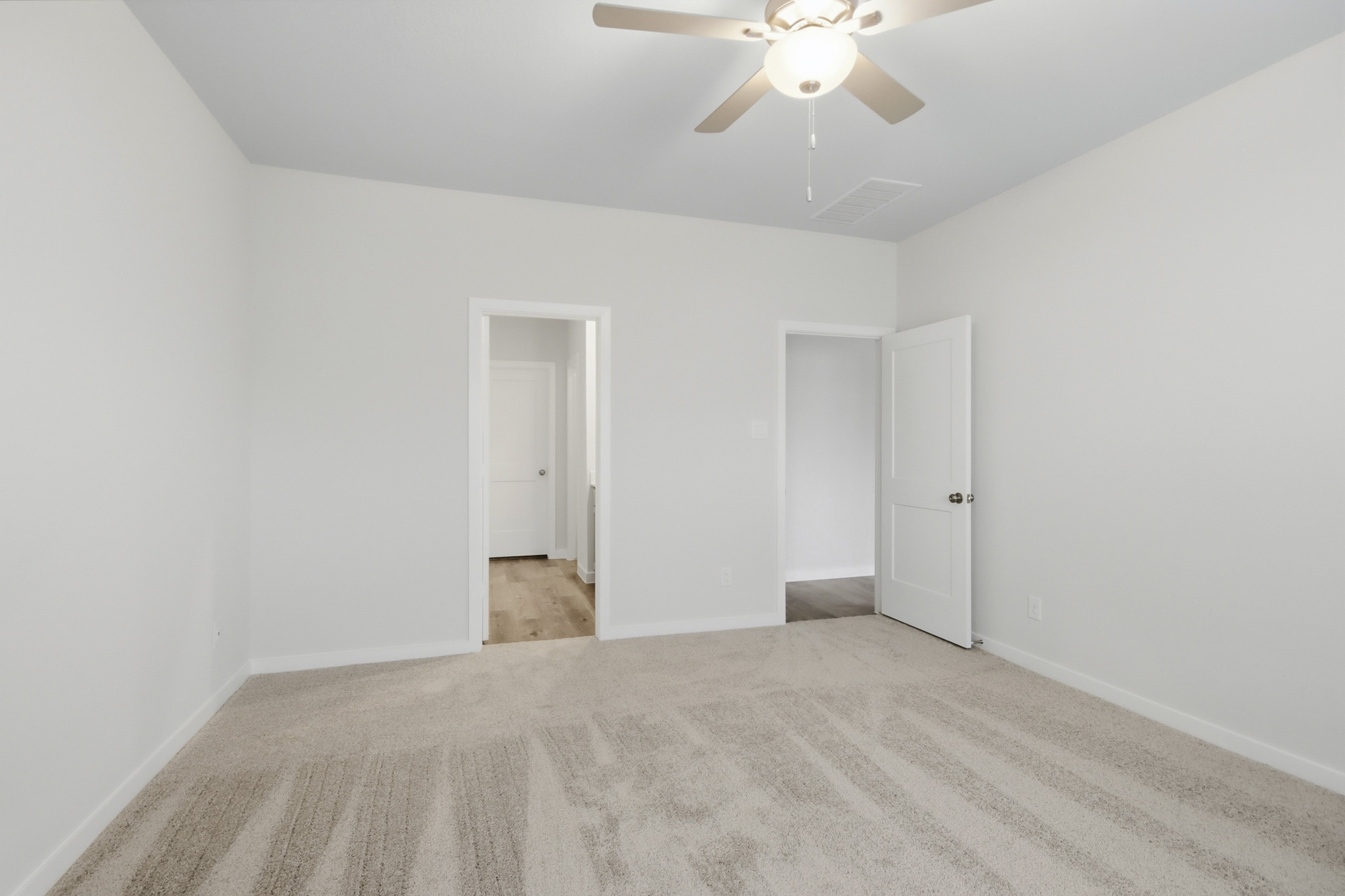 A room with a ceiling fan and a door.