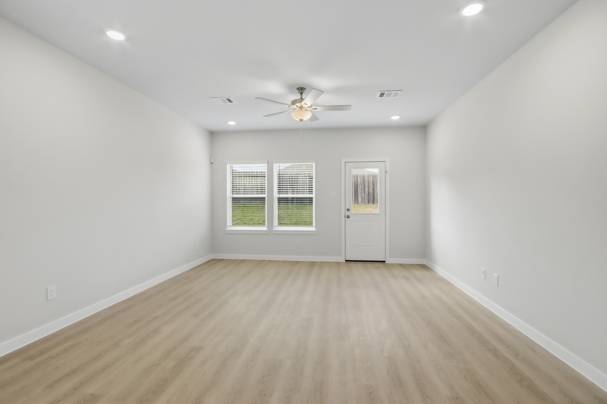 A room with a ceiling fan and a wood floor.