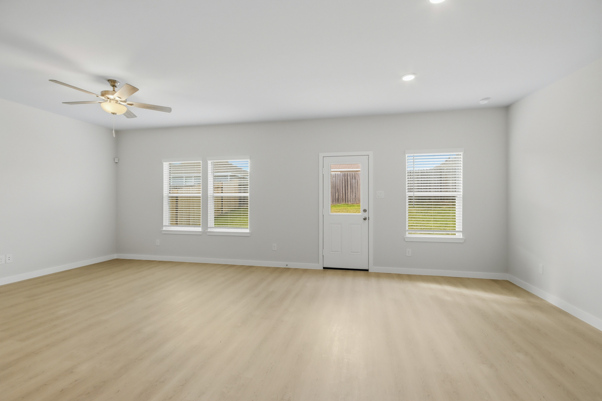A room with a ceiling fan and a wood floor.