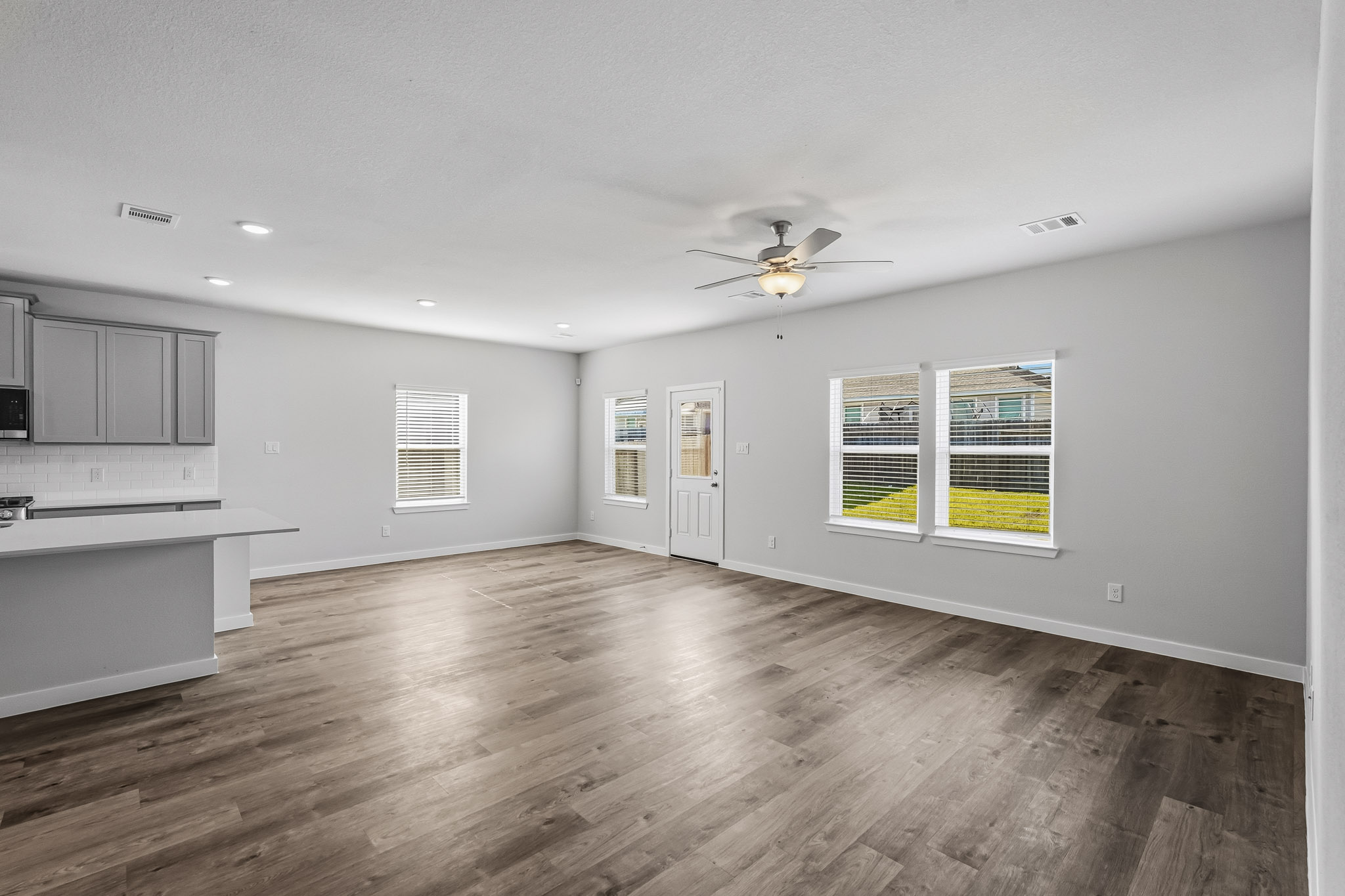 A large empty room with a wood floor and a ceiling fan.