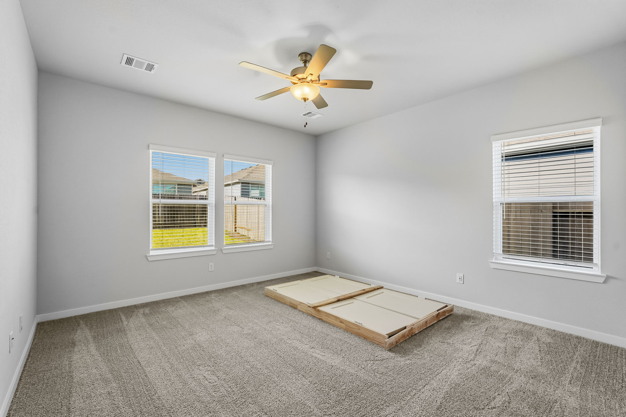 A room with a ceiling fan and a wood box with a window.