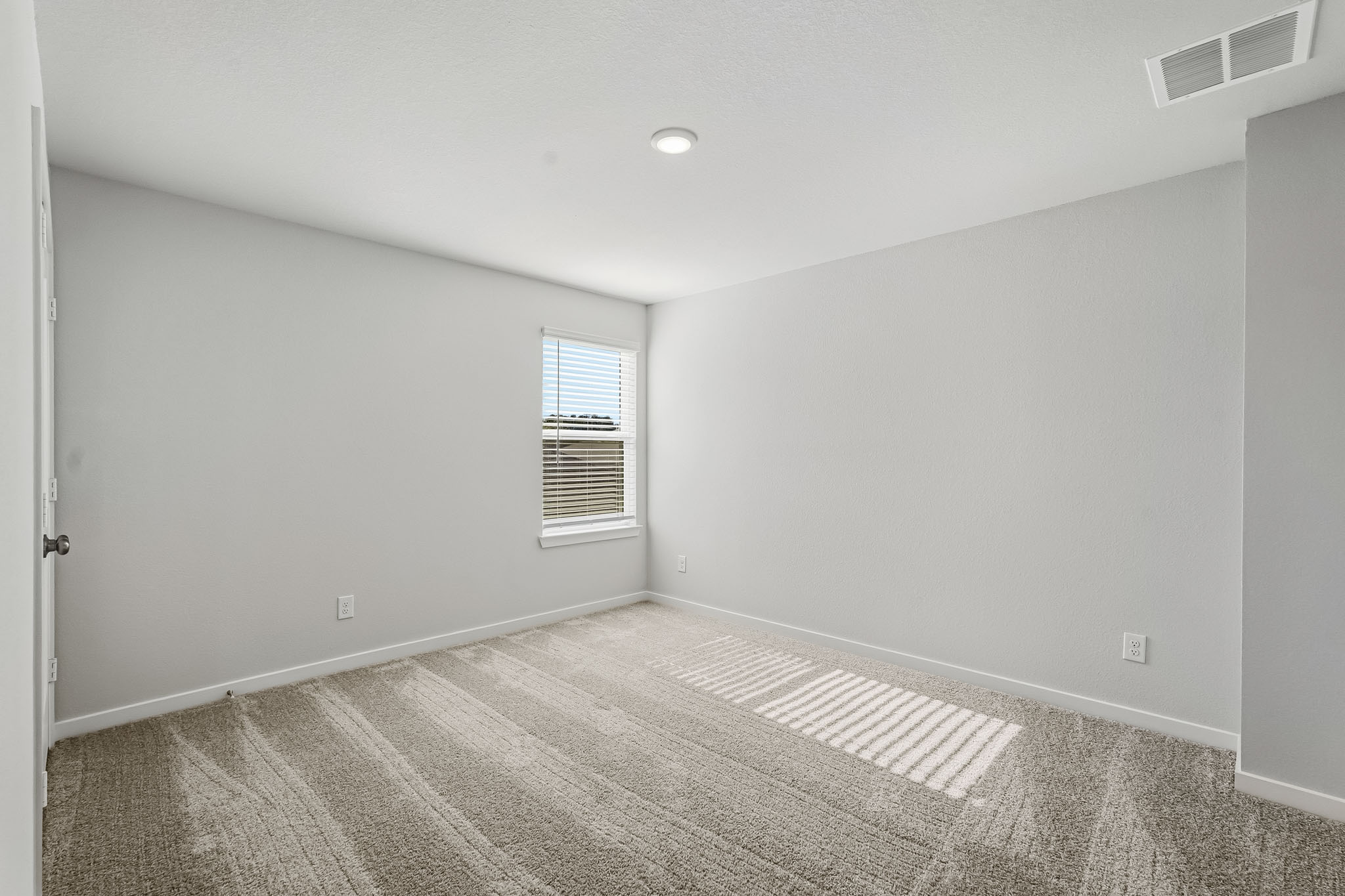 A room with a carpet and a window.