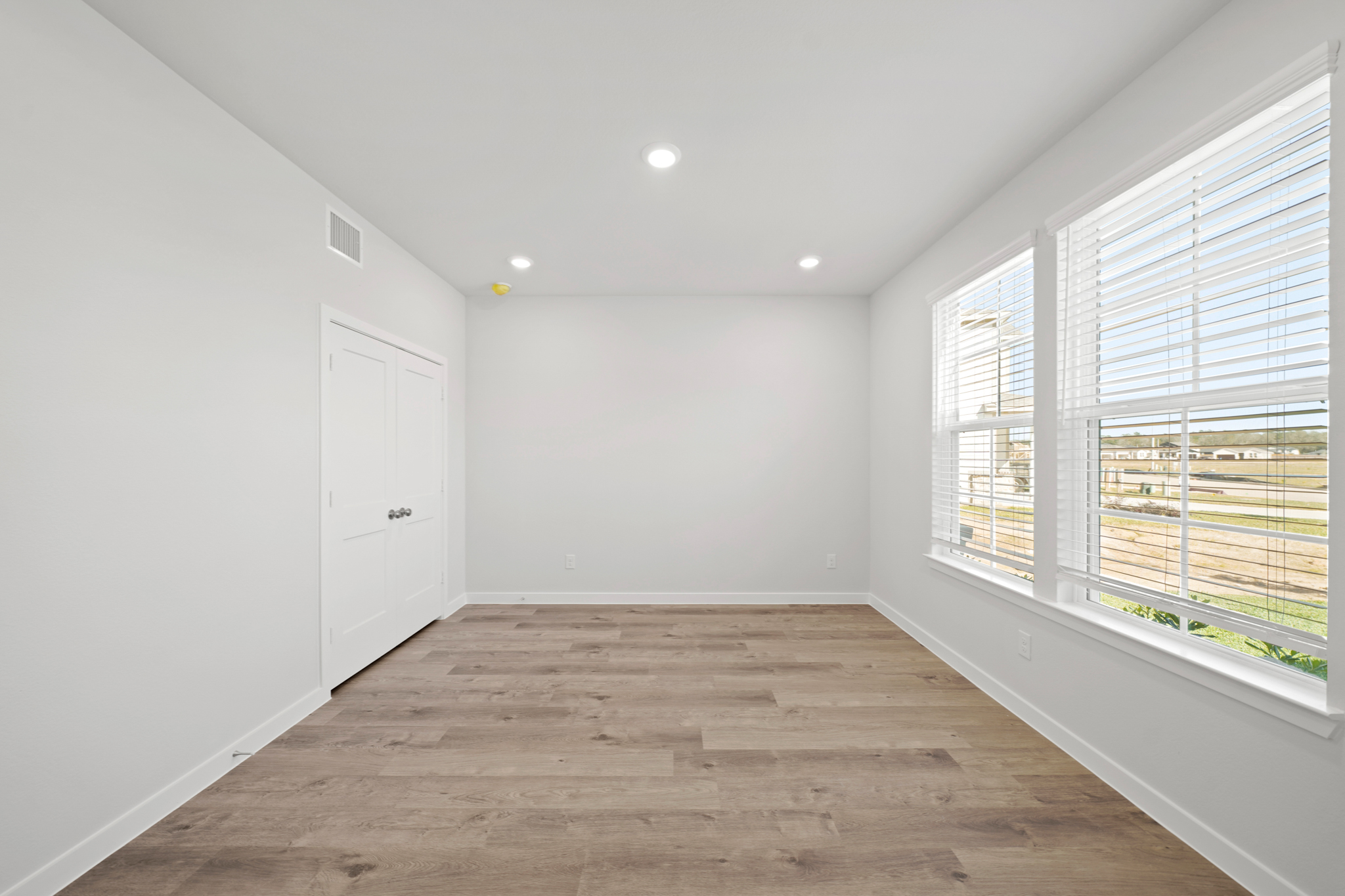 A room with windows and a wood floor.